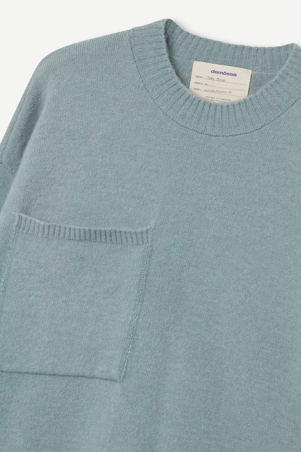 turquoise sweater with a pocket and brand label on a white background