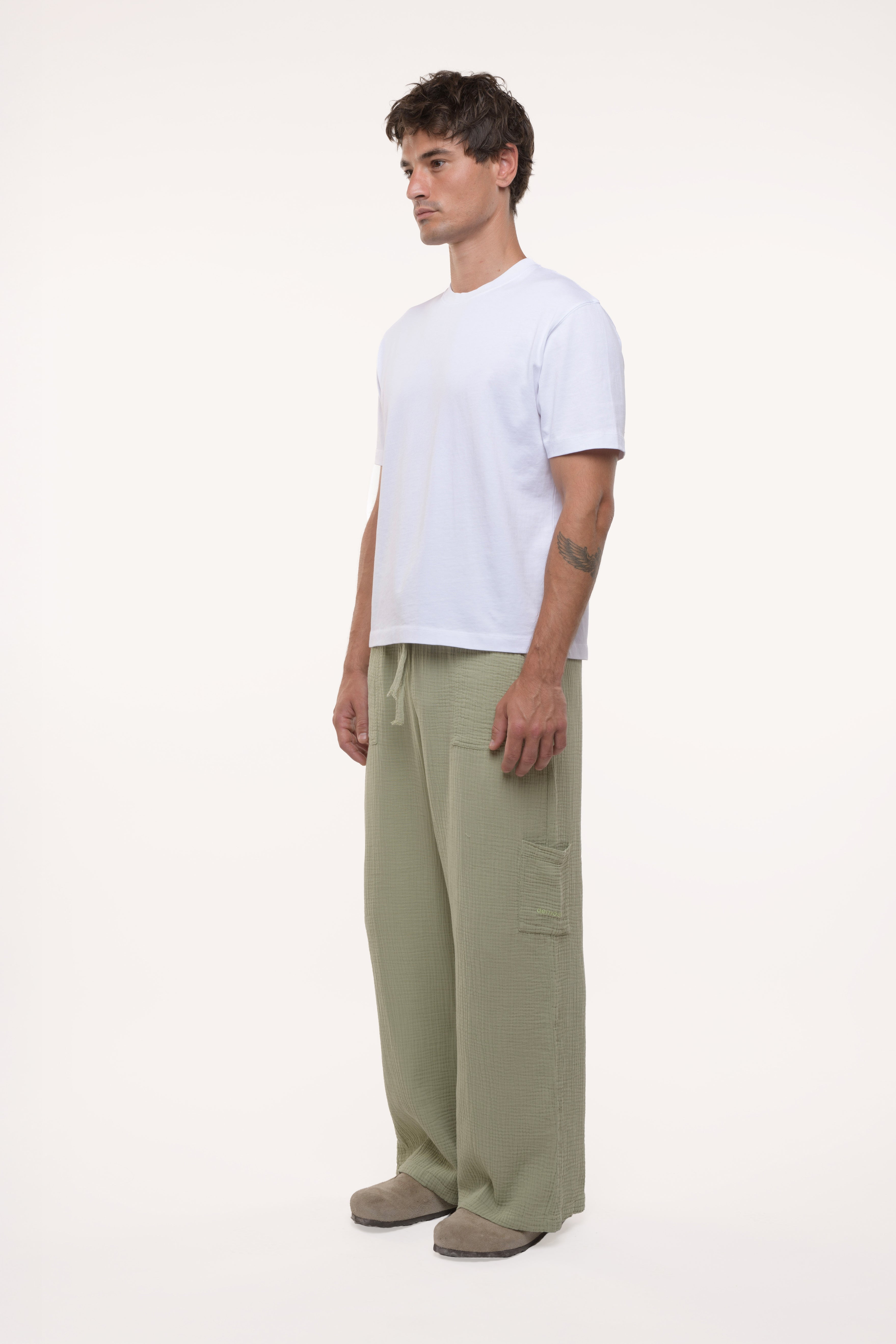 Man wearing a white t-shirt and green cotton pants on a white background