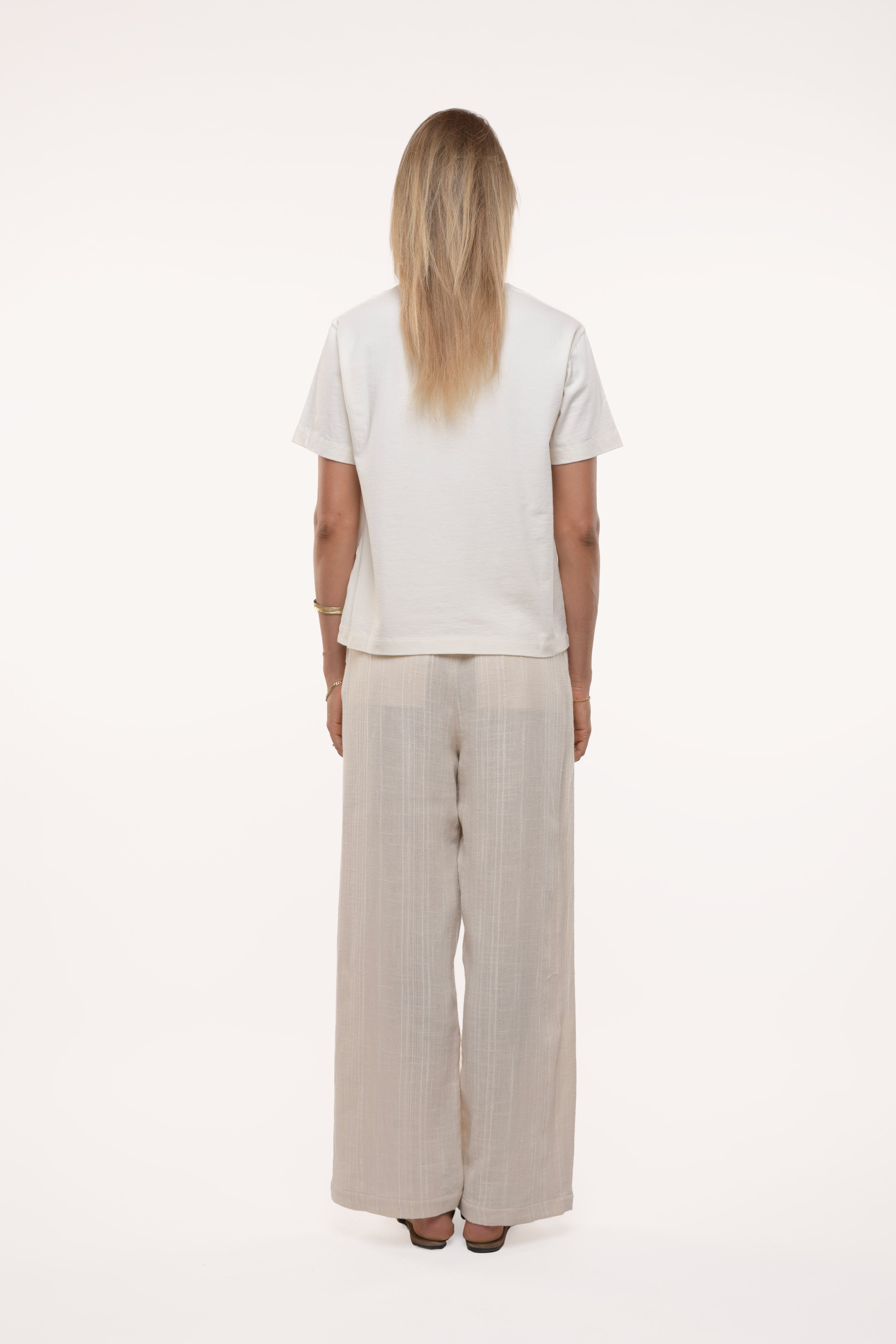 Girl wearing a white t-shirt and beige wide-leg pants on a white background