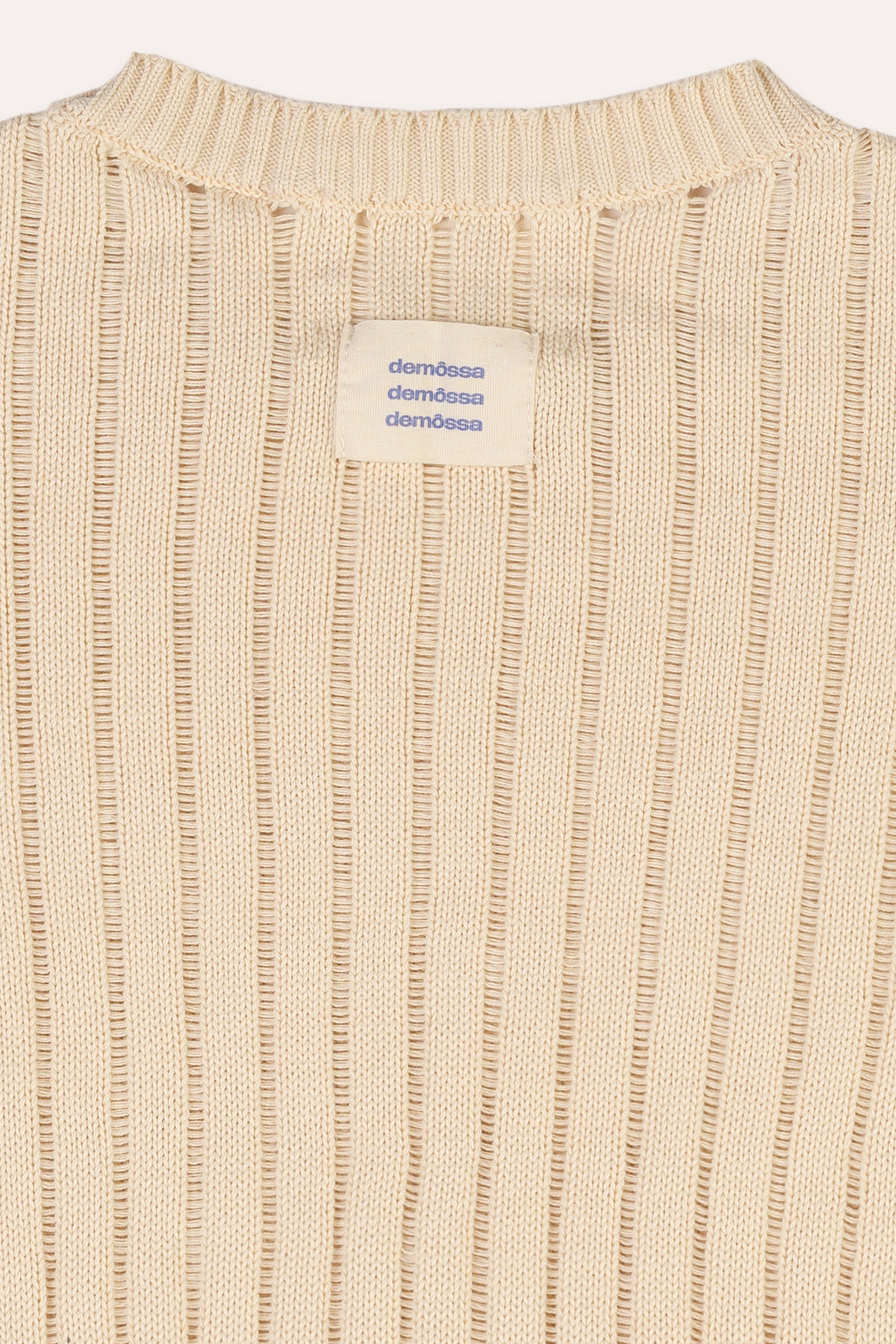 Close-up of a beige ribbed sweater with a brand label on a white background