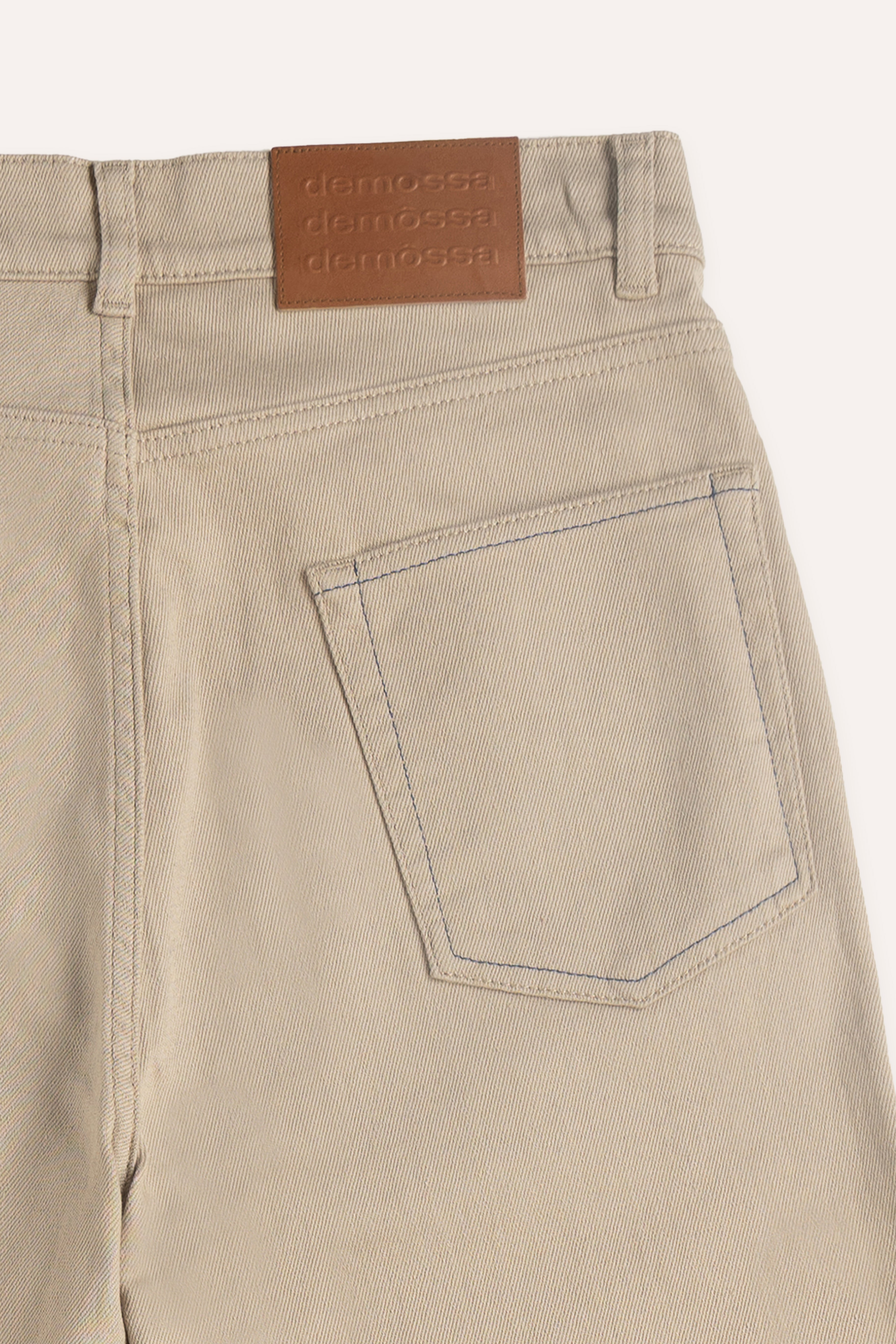 Close-up of branded jacron patch on the back waistband featuring triple Demossa logo
