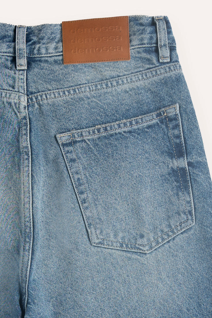 Close-up of leather jacron patch on waistband, embossed with triple Demossa logo