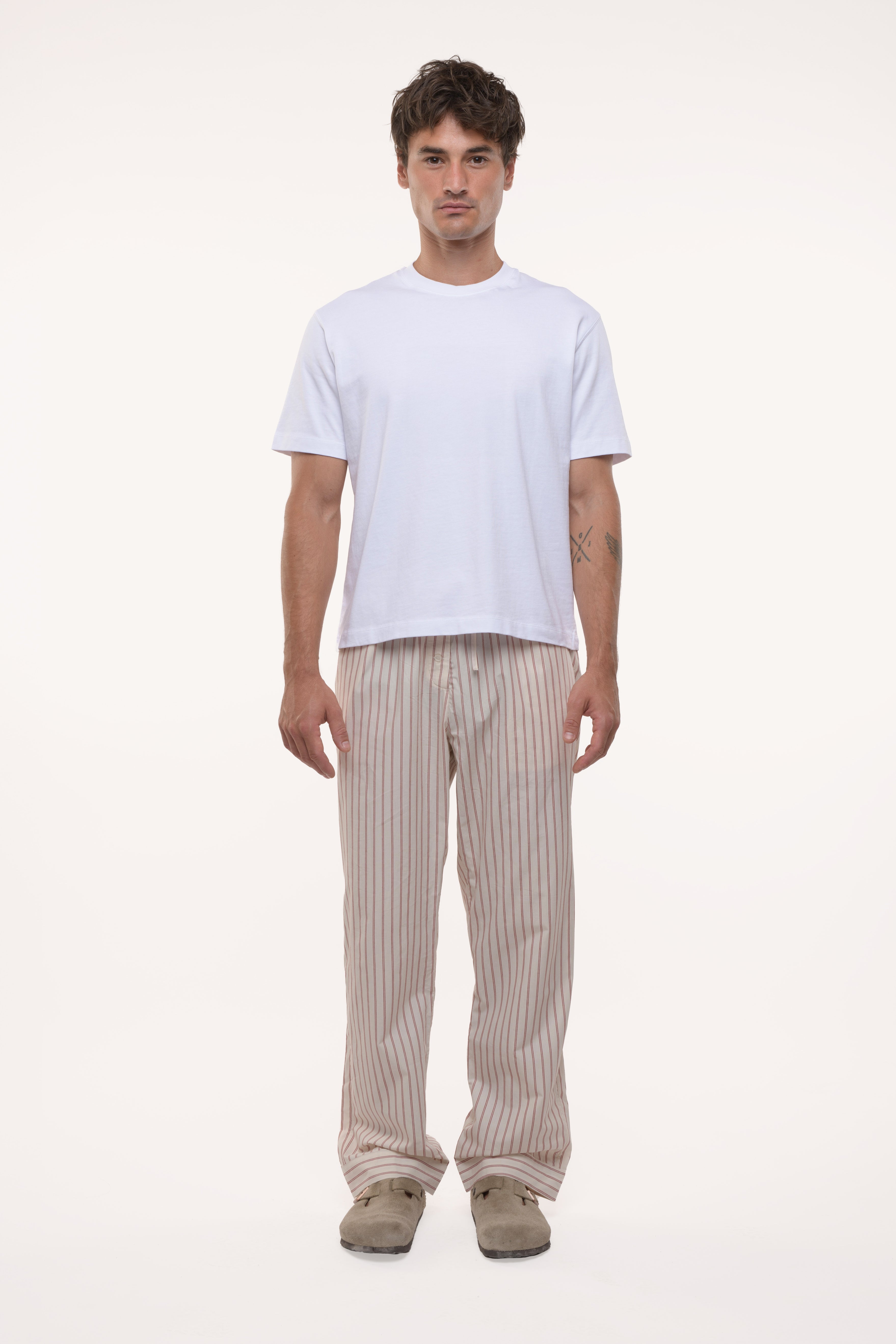 Man wearing a white t-shirt and beige striped cotton pants on a white background