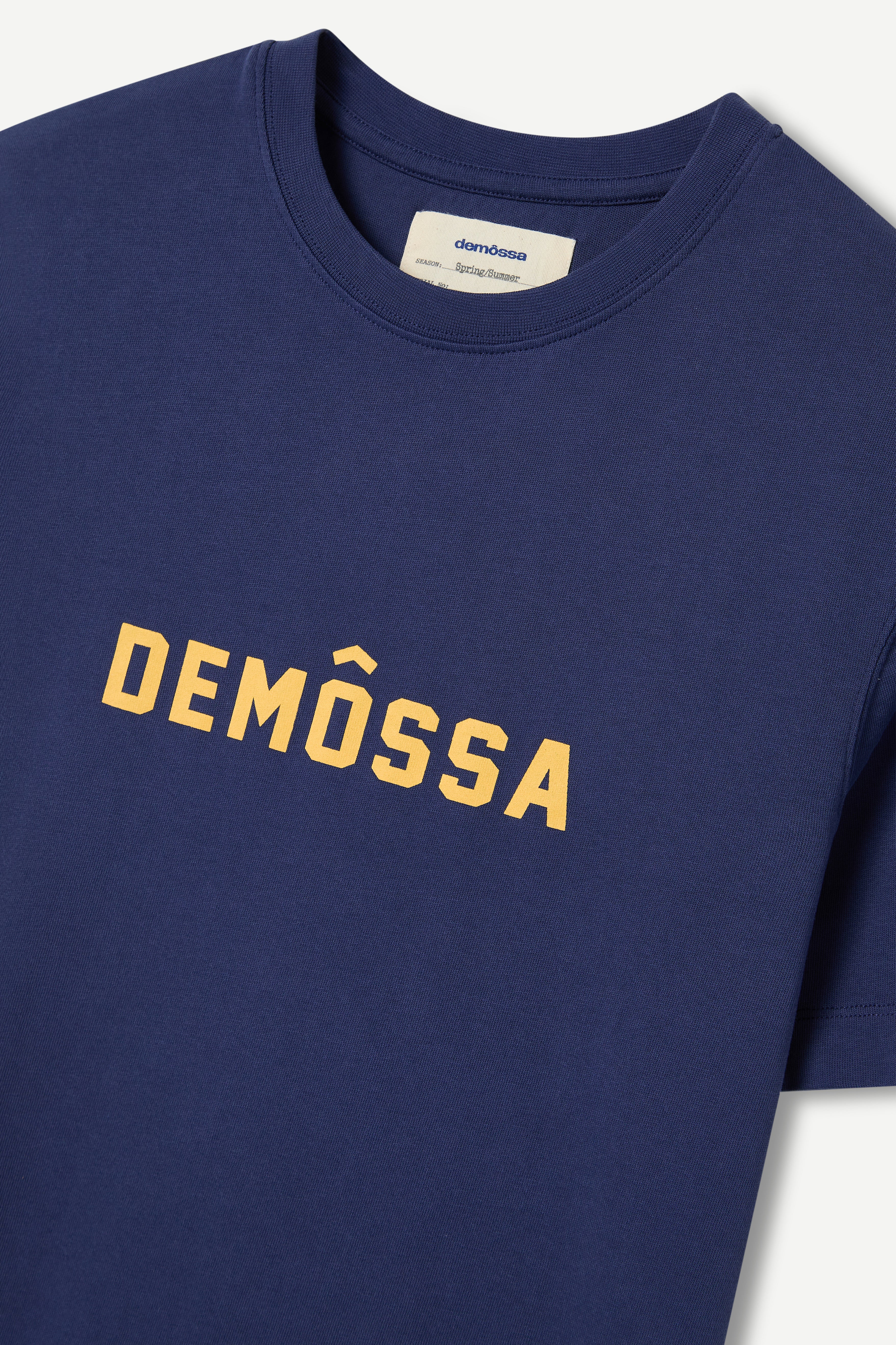 Navy blue t-shirt with 'DEMOSSA' printed in yellow on a white background