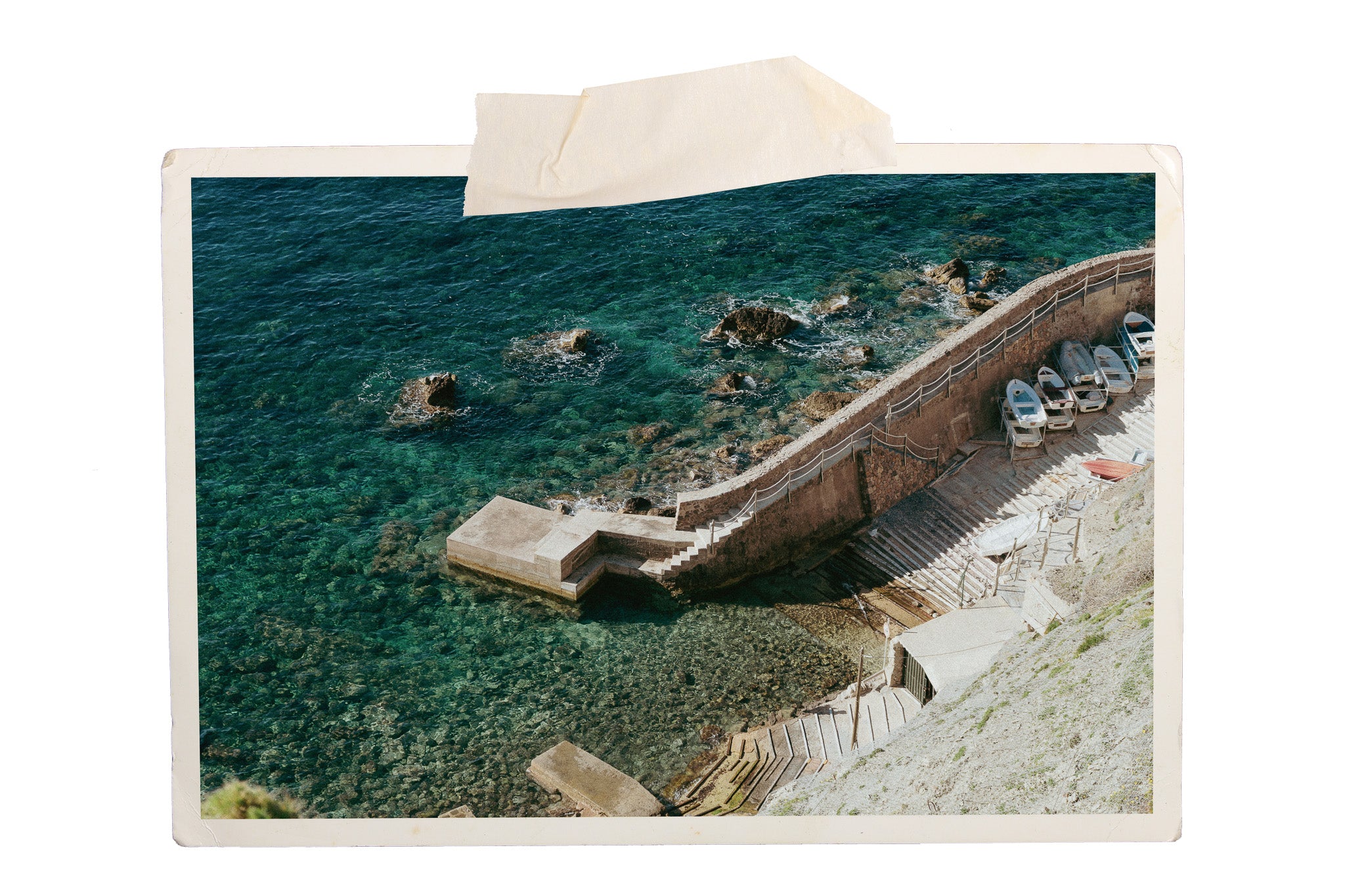 Mediterranean cove with clear blue water and a small rustic dock where small boats are stored