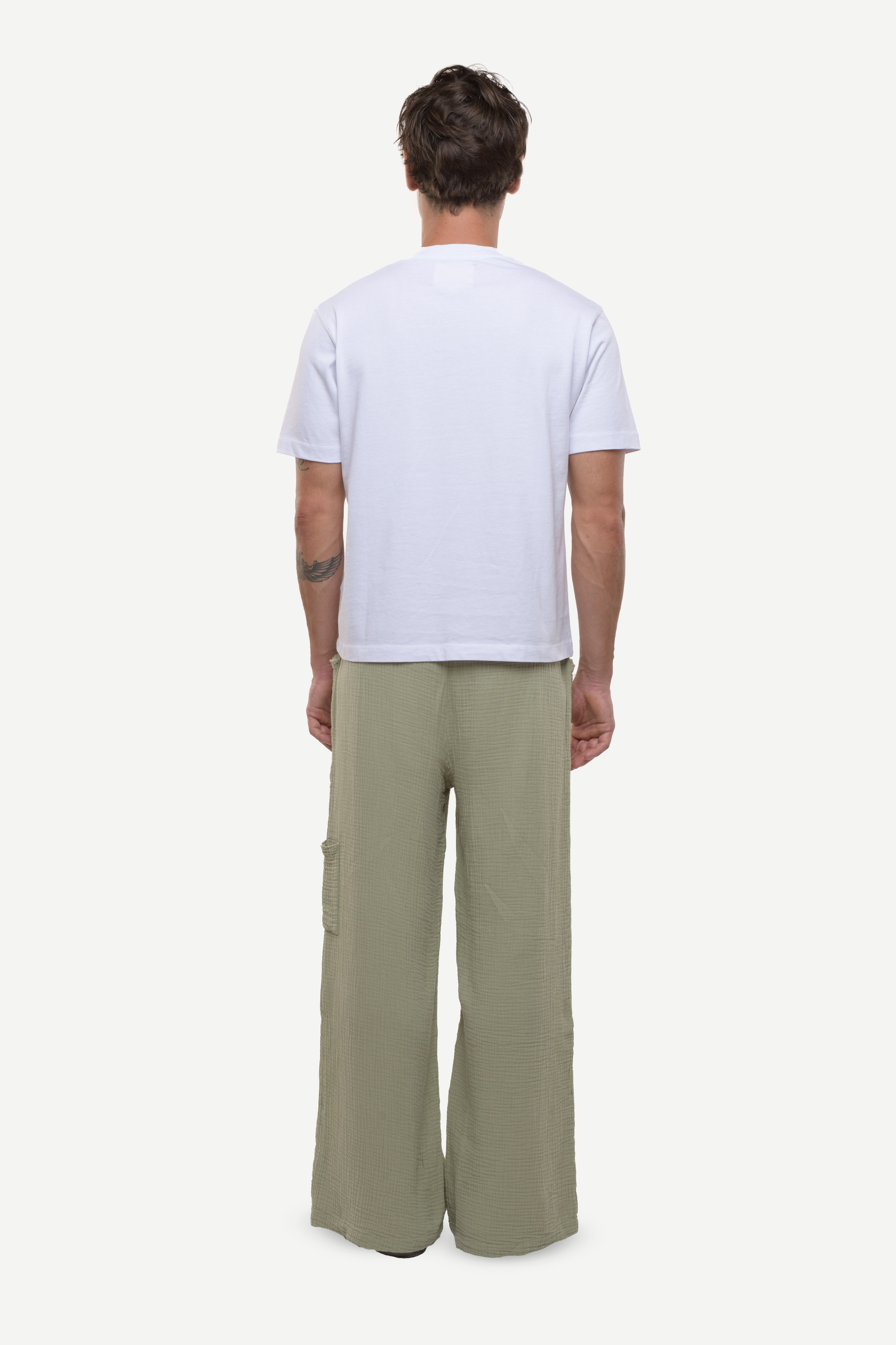 Back view of a man wearing a white t-shirt and cotton green pants on a white background