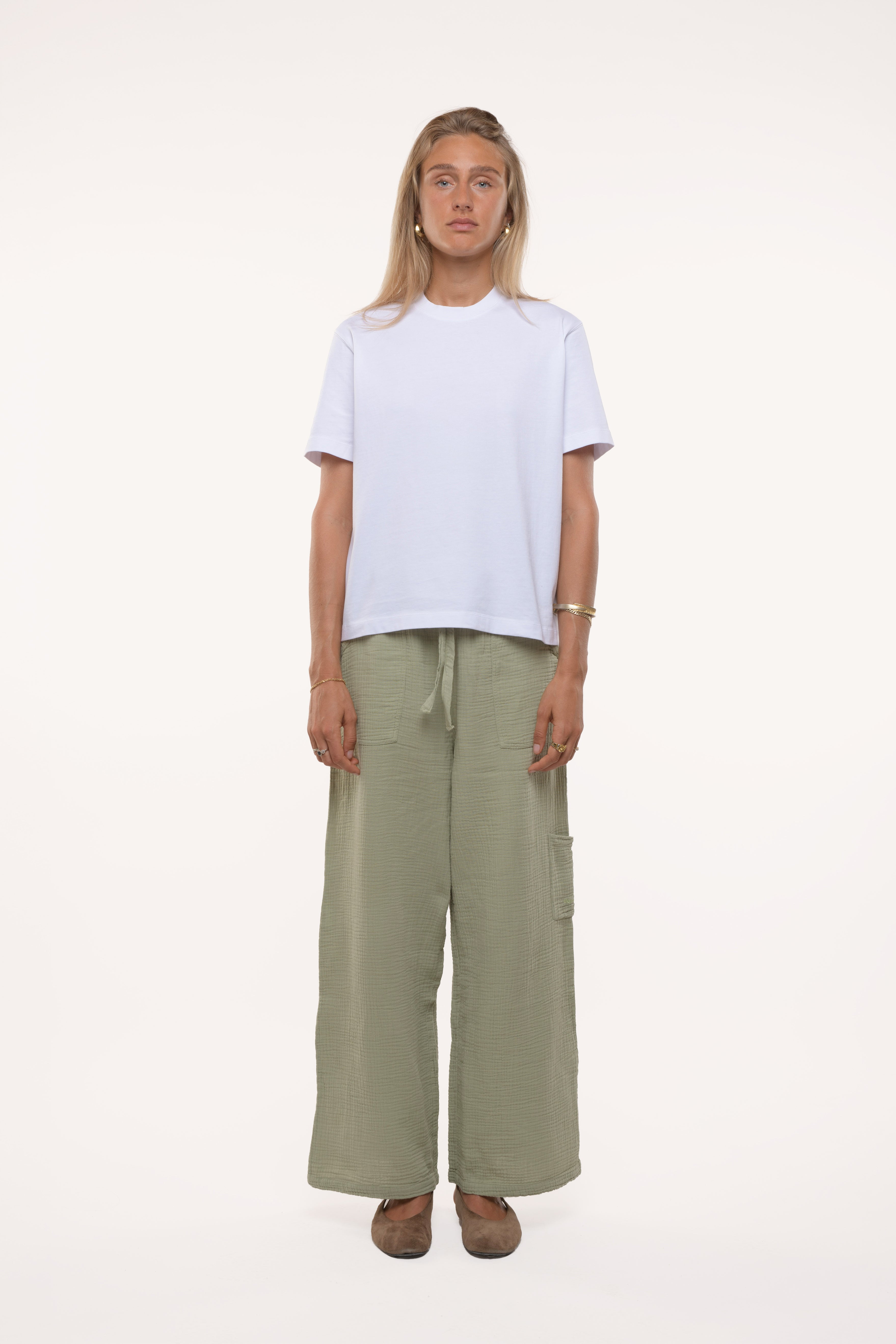Woman wearing a white t-shirt and green cotton pants on a white background