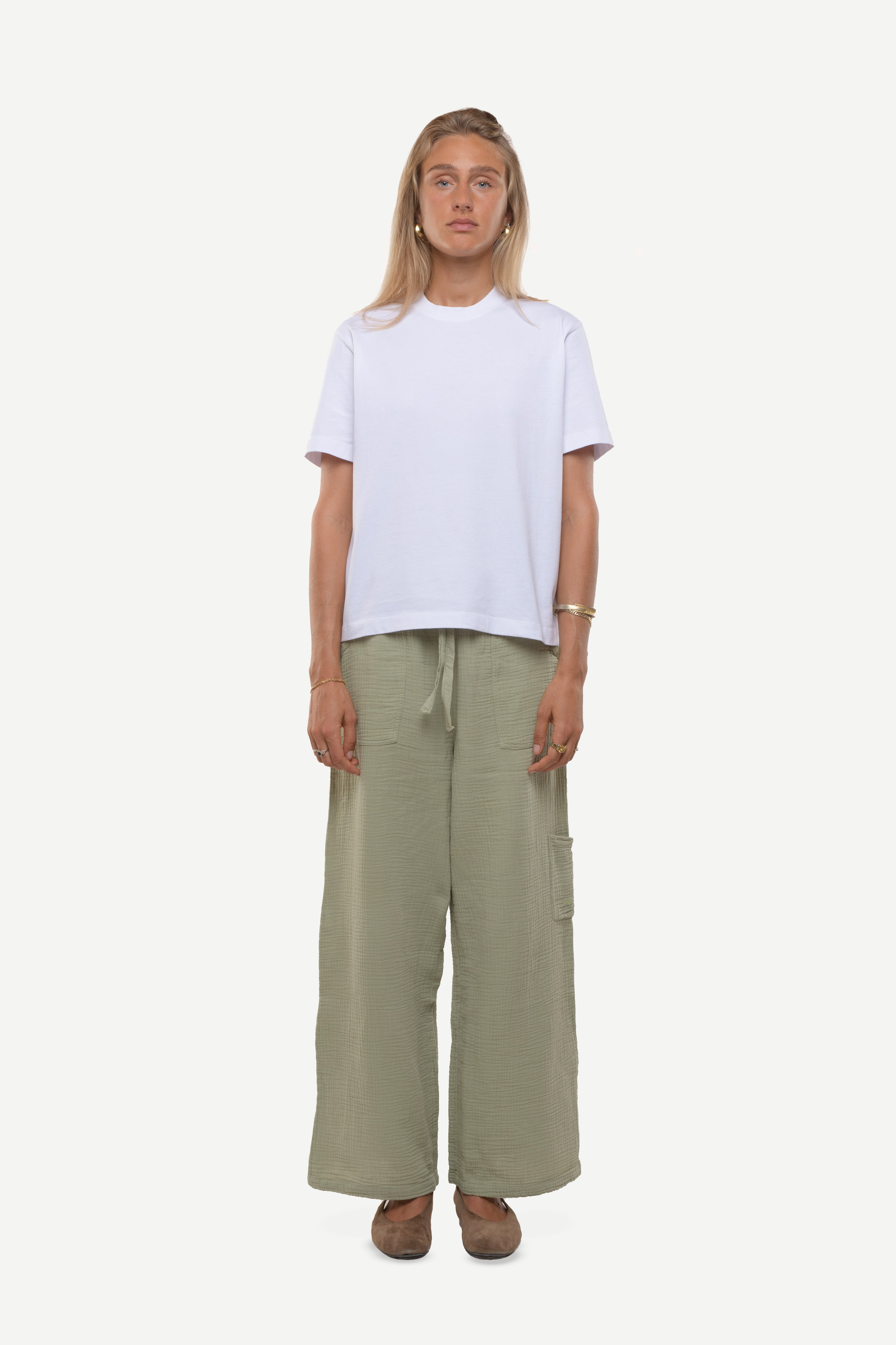 Woman wearing a white t-shirt and cotton green pants on a white background