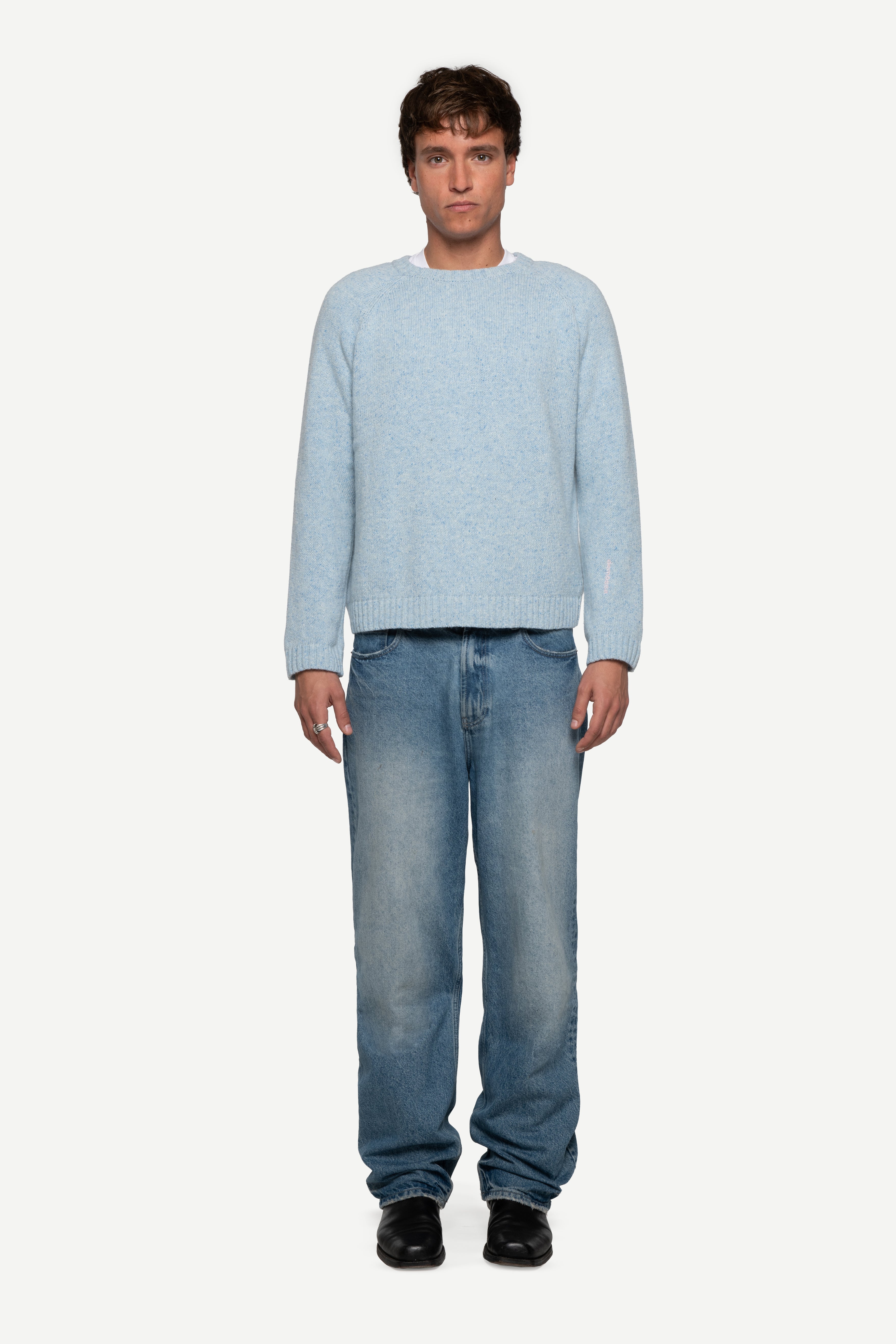 front view of man wearing a blue sweater made from a soft blend of wool and silk with black jeans on a white background