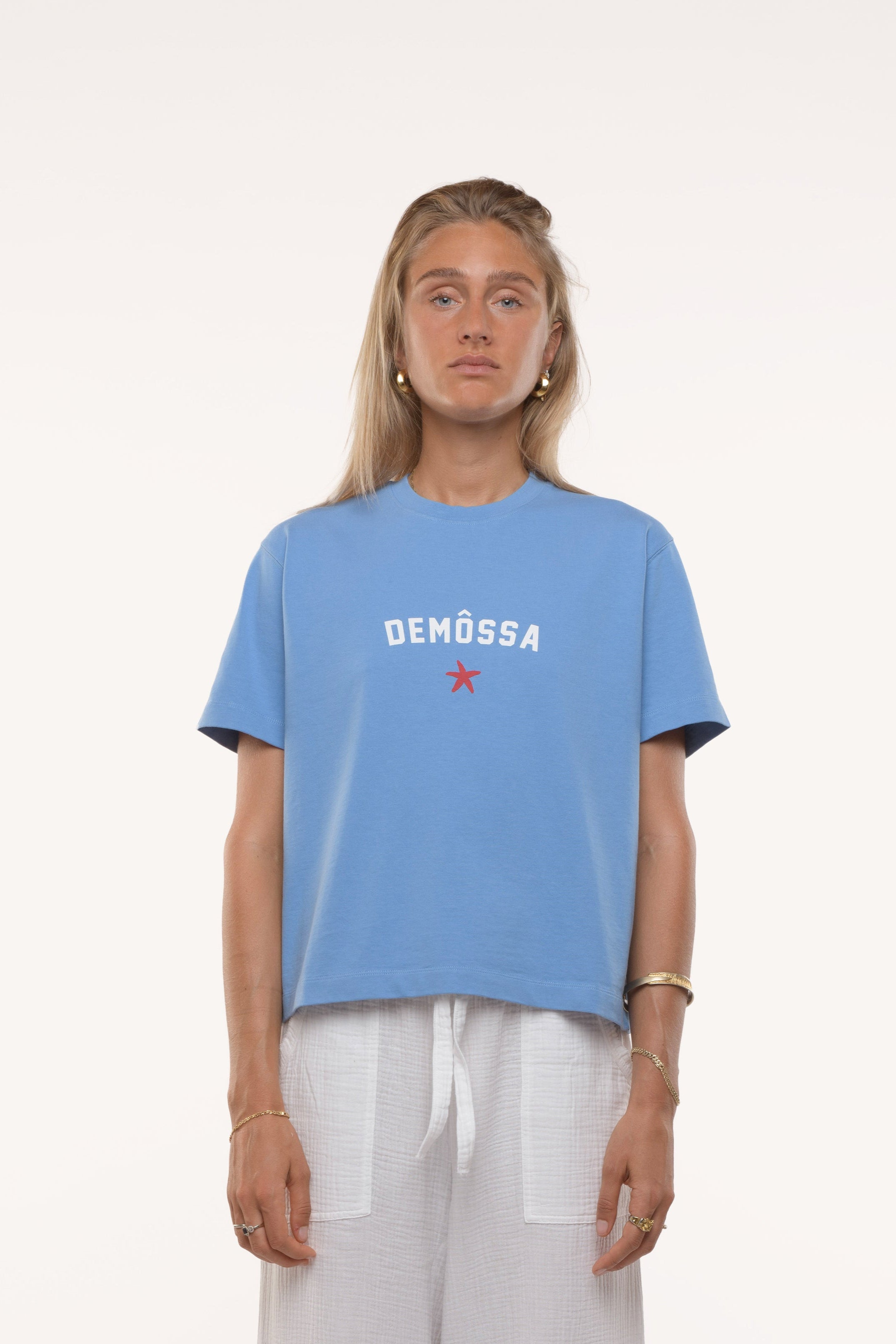 Person wearing a blue t-shirt with 'DEMOSSA' logo on a white background