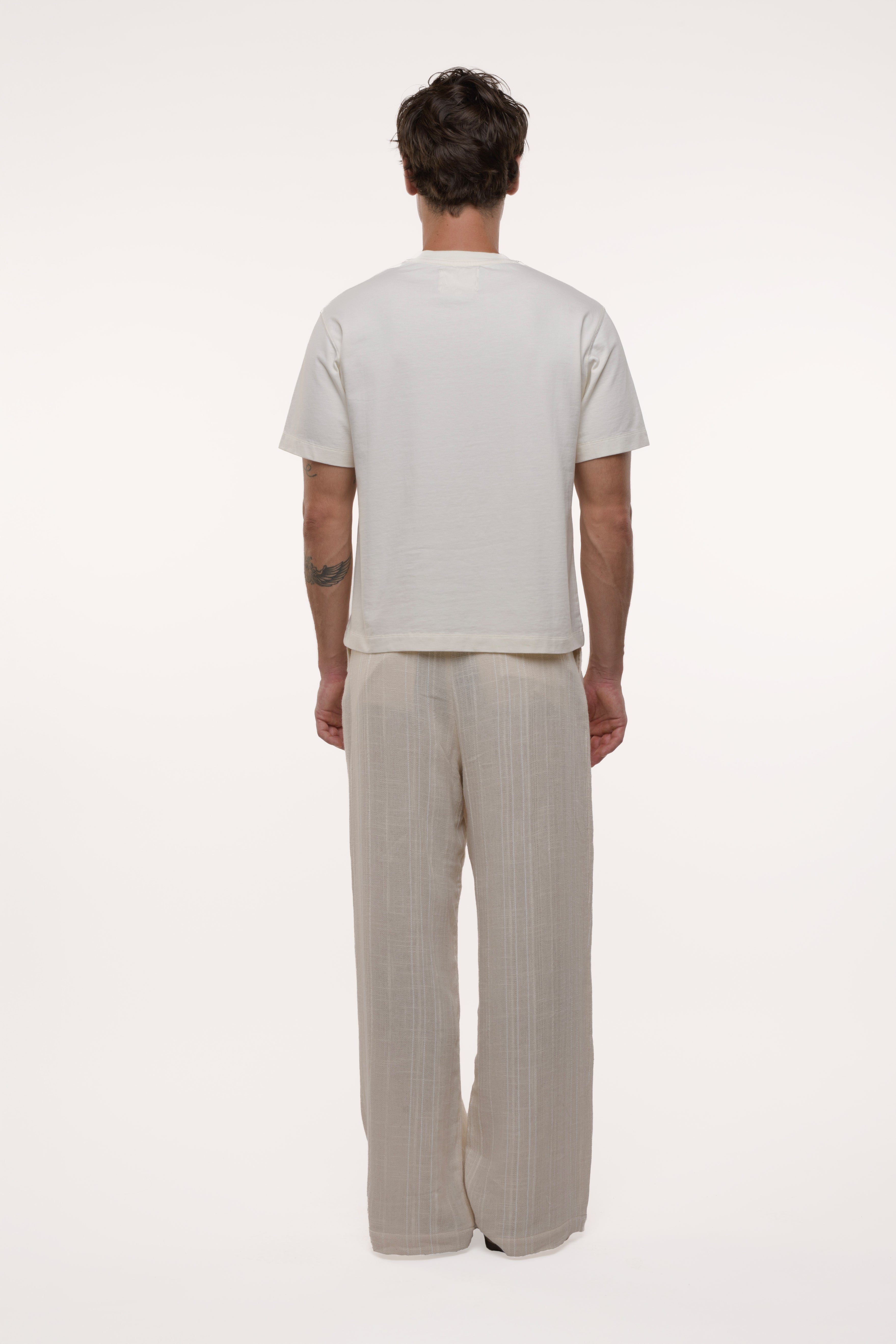 Man wearing a plain white t-shirt and beige pants on a white background