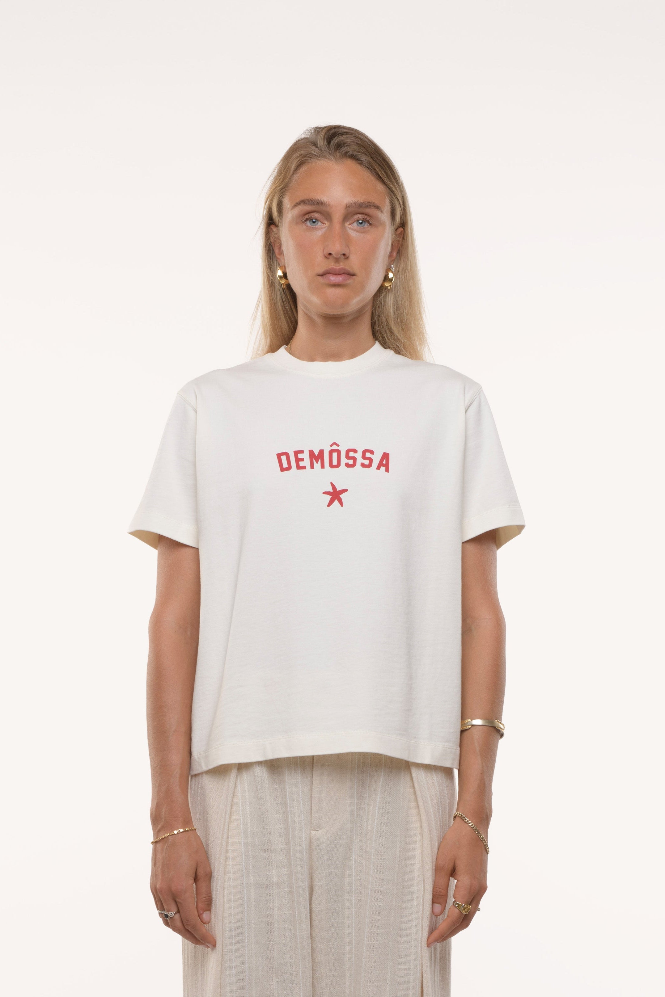 Girl wearing a white t-shirt with red text and beige pants on a white background