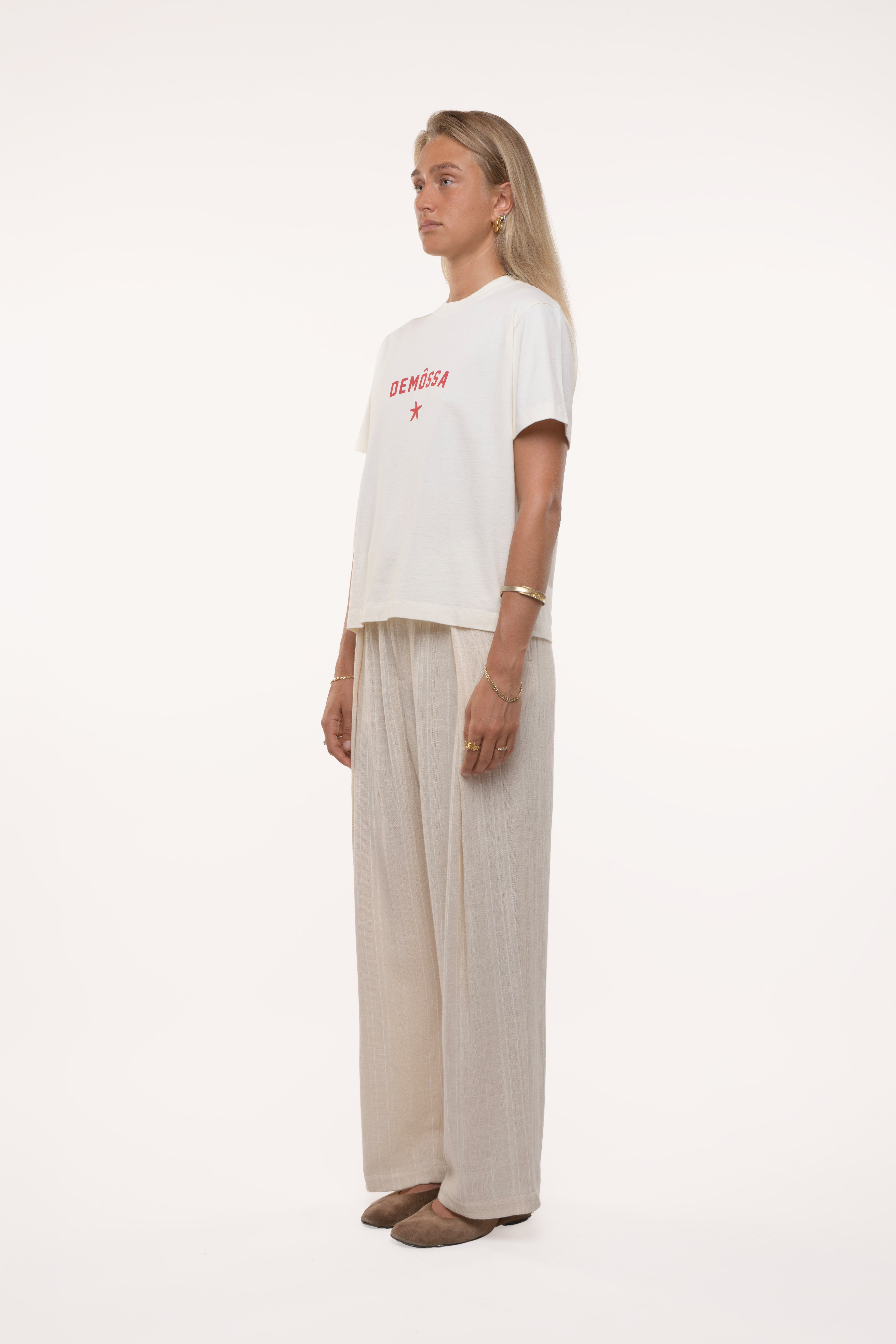 Girl wearing a white t-shirt with red text and beige pants on a white background