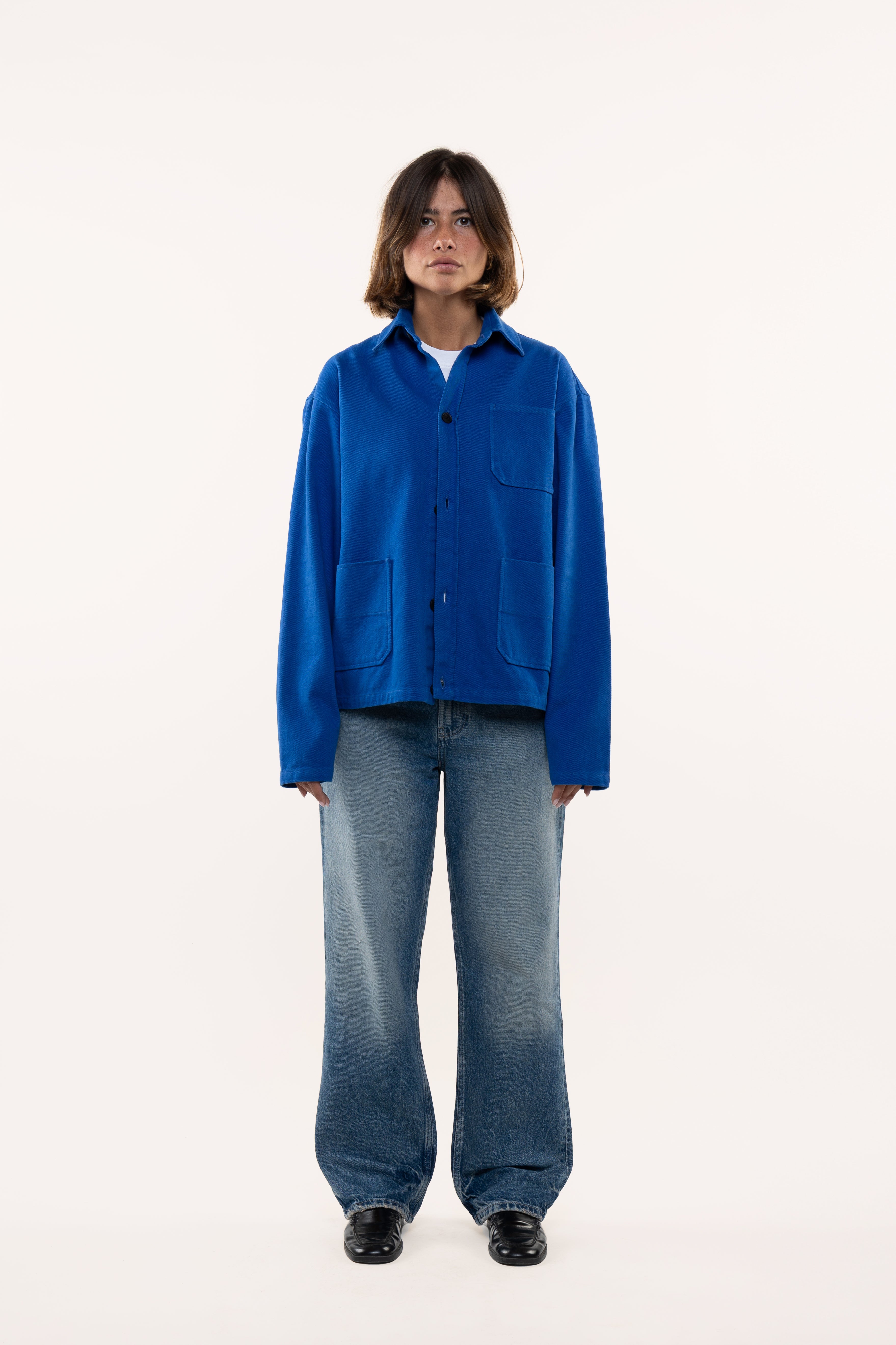 Woman wearing a blue overshirt and jeans on a white background