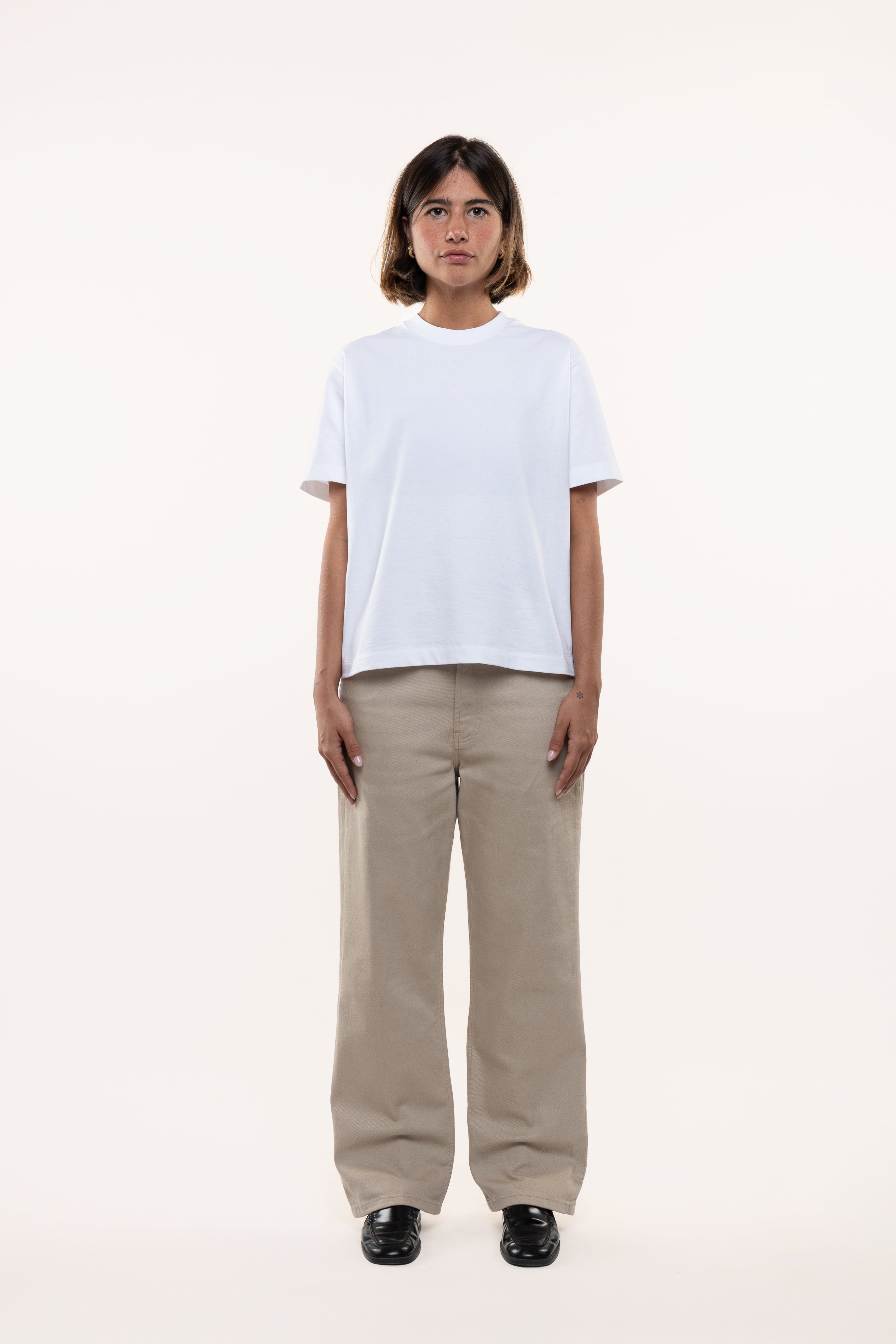 Woman wearing a white t-shirt and beige pants on a white background