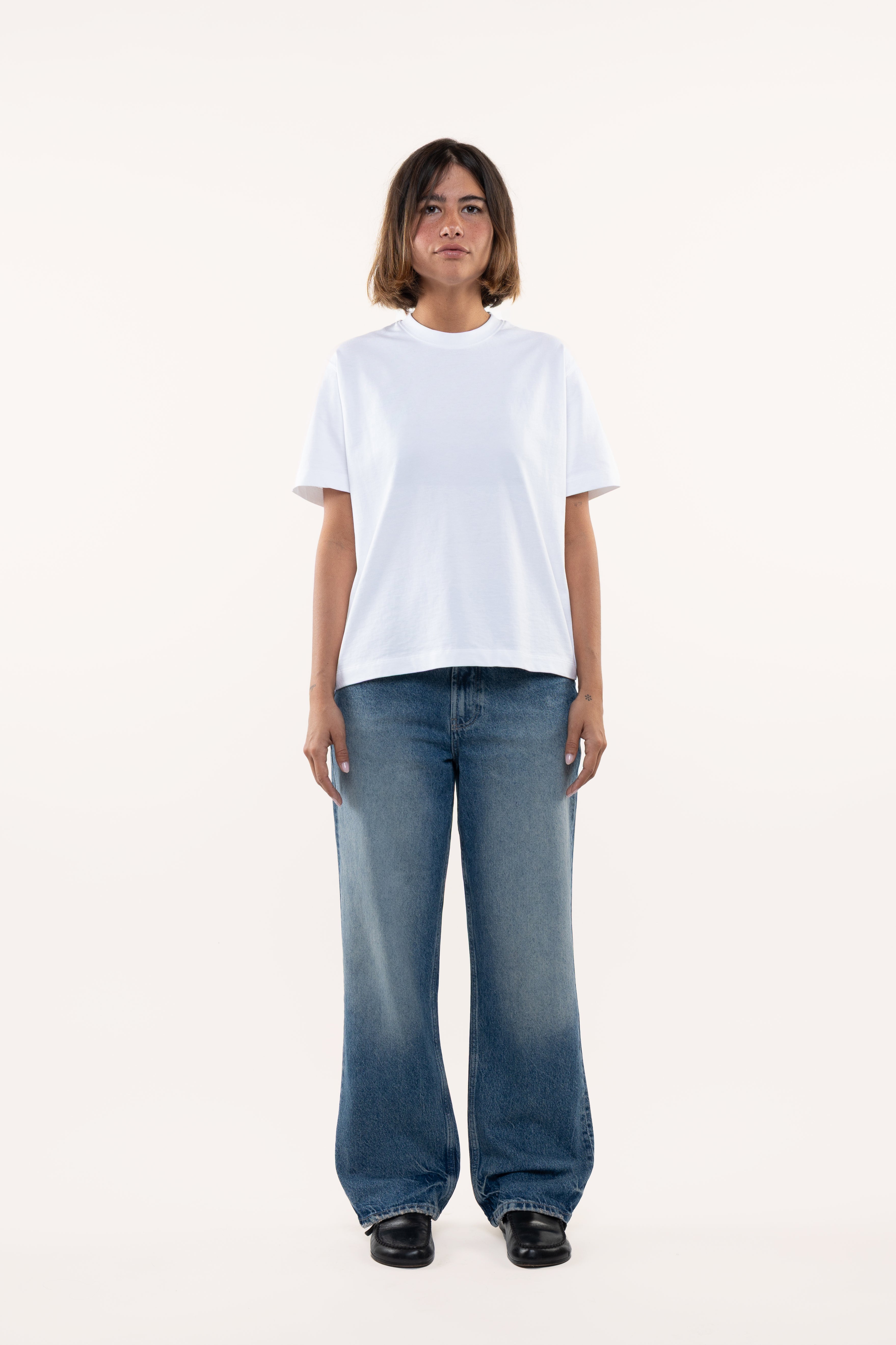 Woman wearing a white t-shirt and blue jeans on a white background
