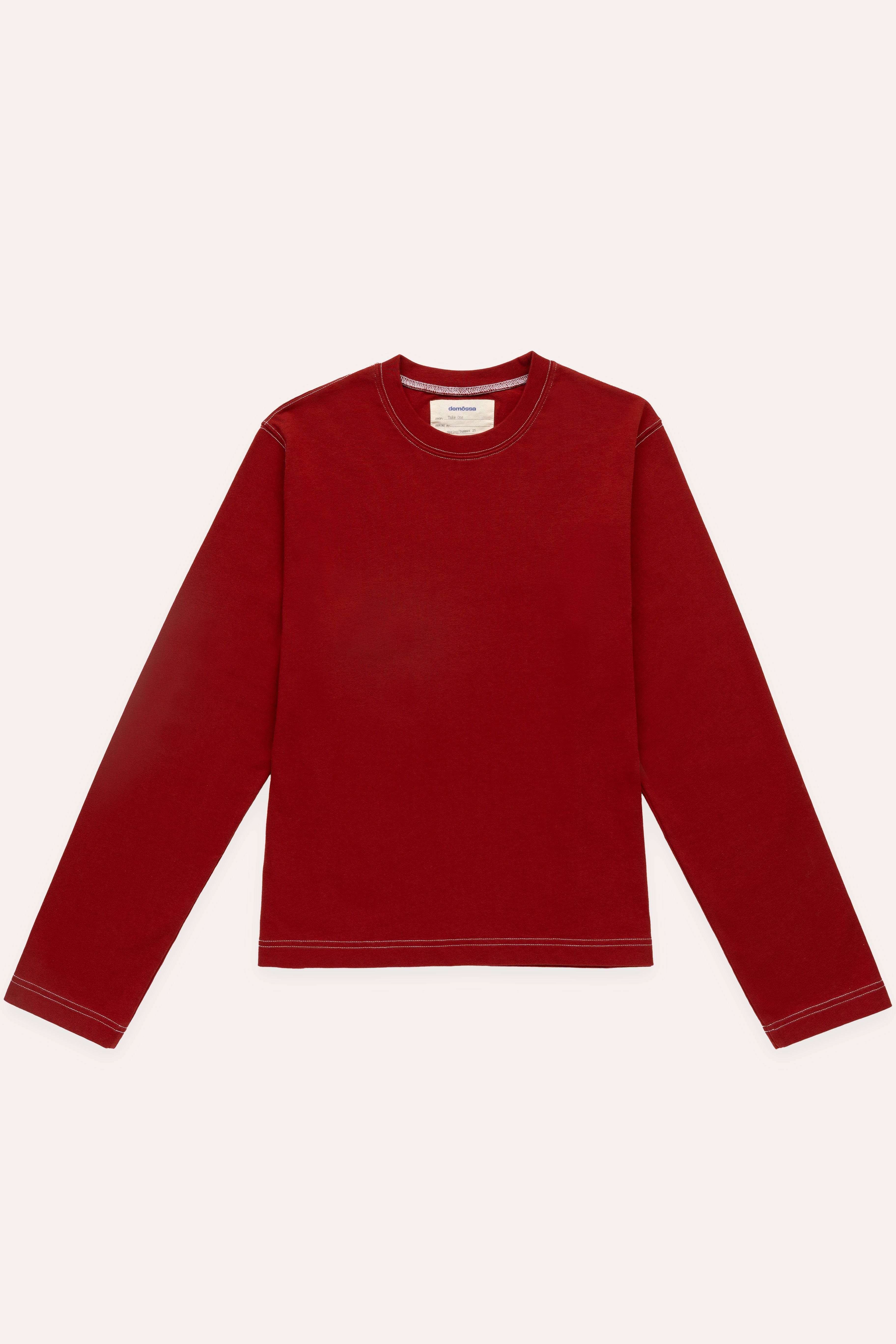 Flat lay of red long-sleeve T-shirt with exposed white stitching on shoulders, sleeves, and hem