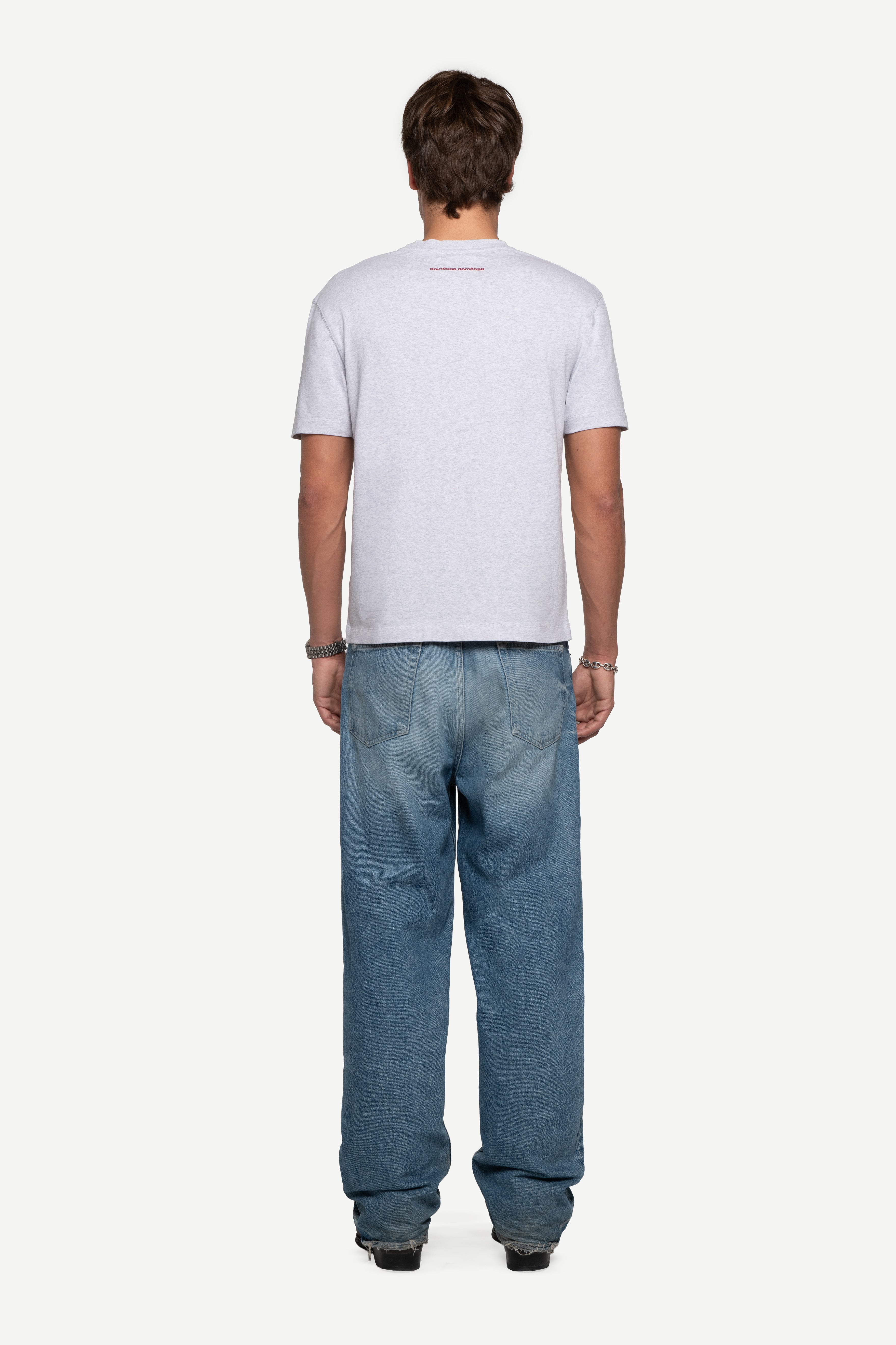 back view of man wearing a regular fit short-sleeved grey melange t-shirt with blue jeans on a white background