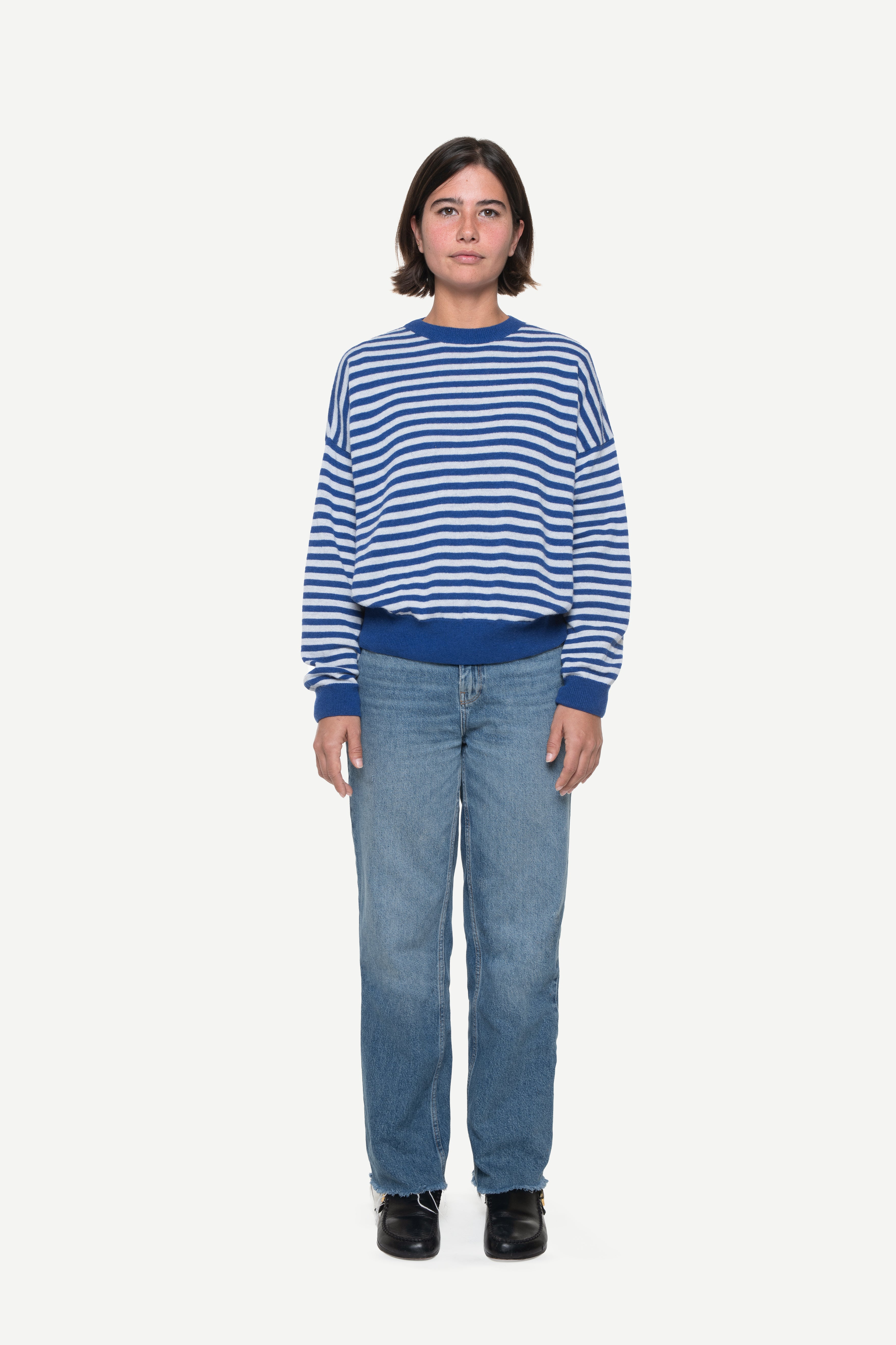 woman wearing a blue knit striped sweater and jeans on a white background