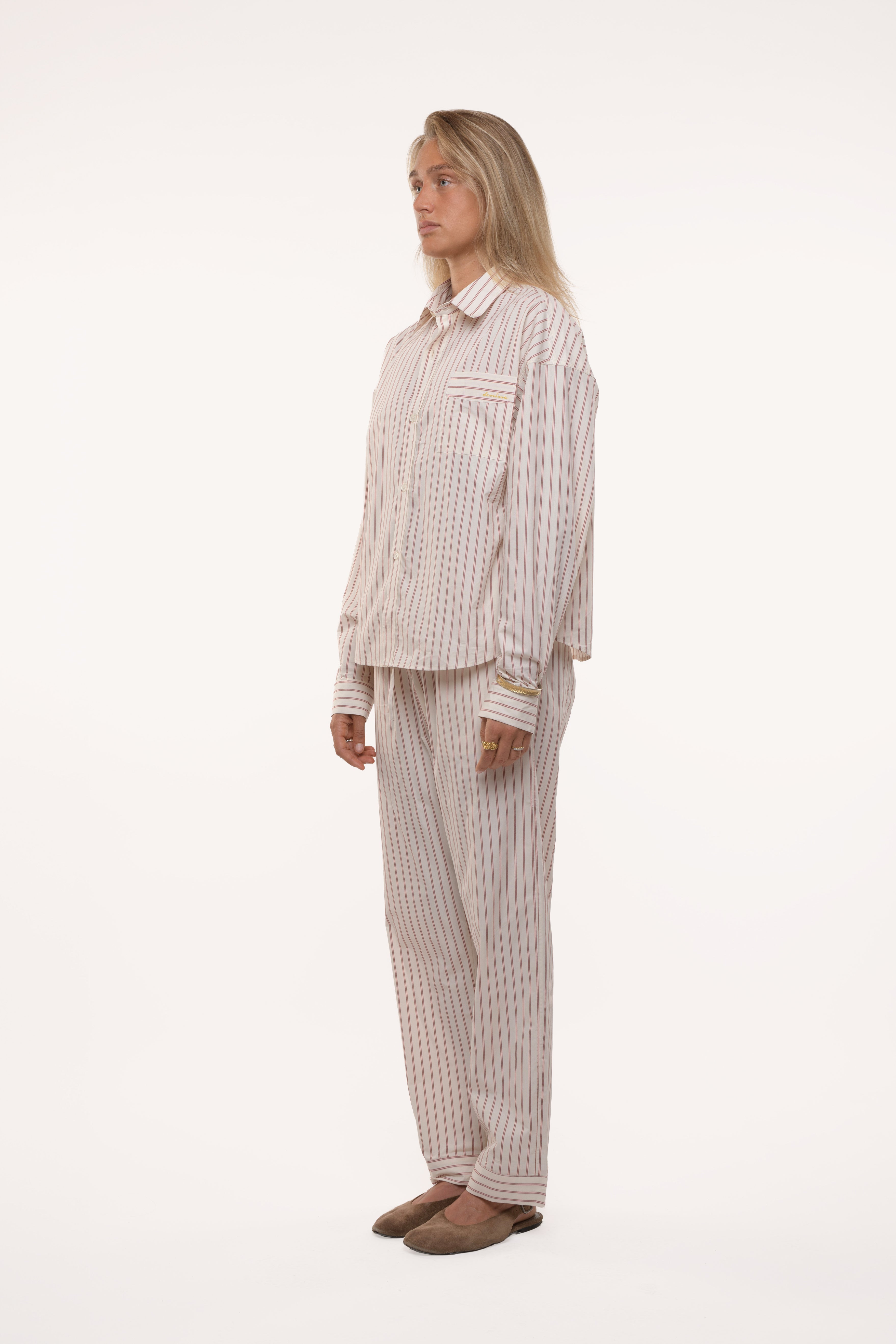 Side videw of a woman wearing a striped pajama set on a white background