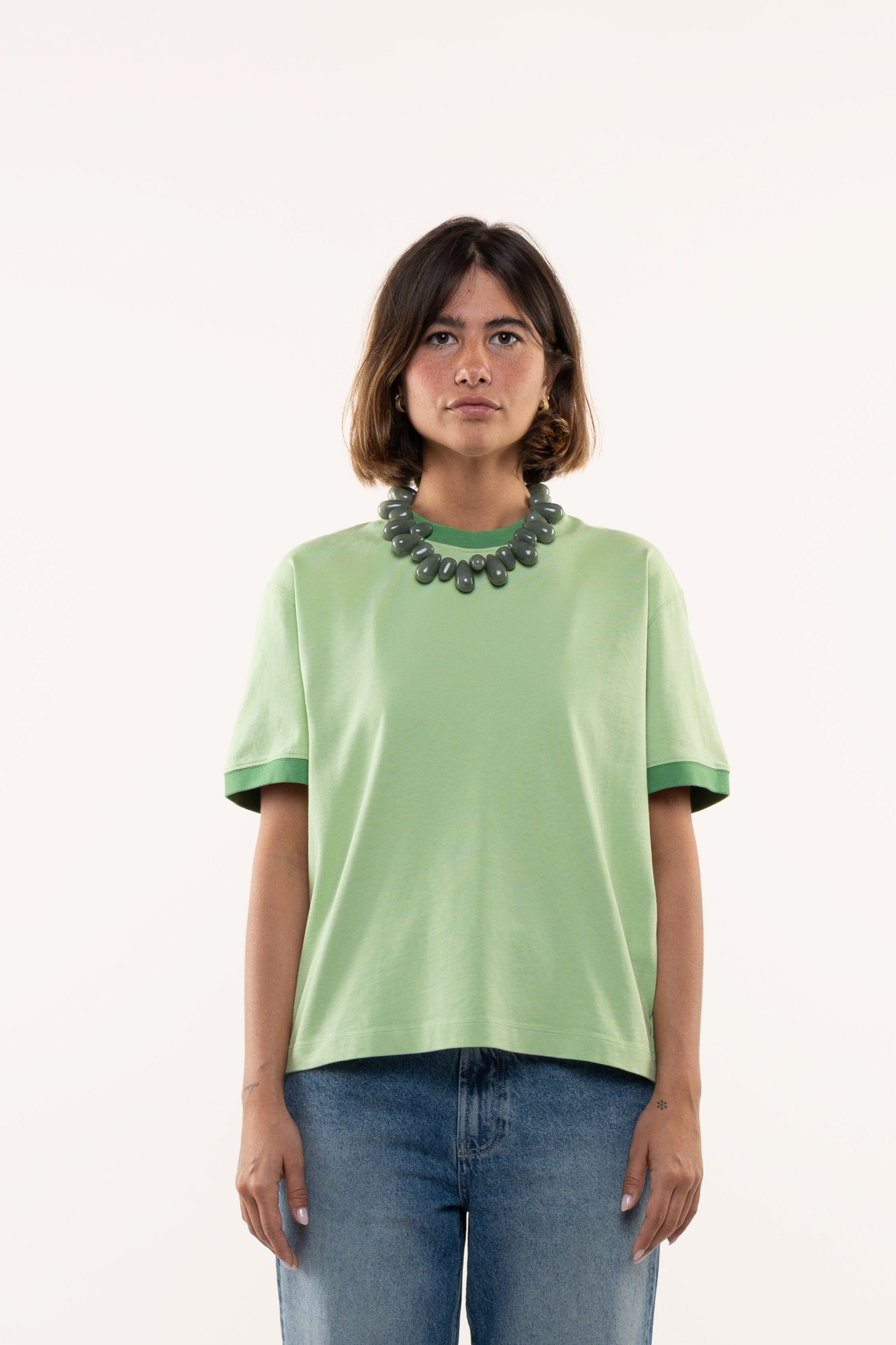 Person wearing a green shirt and blue jeans on a white background