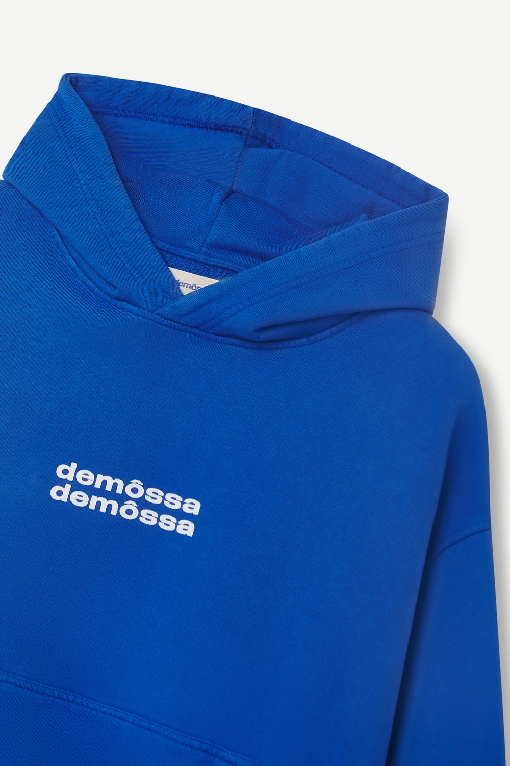 Blue hoodie with 'demôssa' branding on a white background