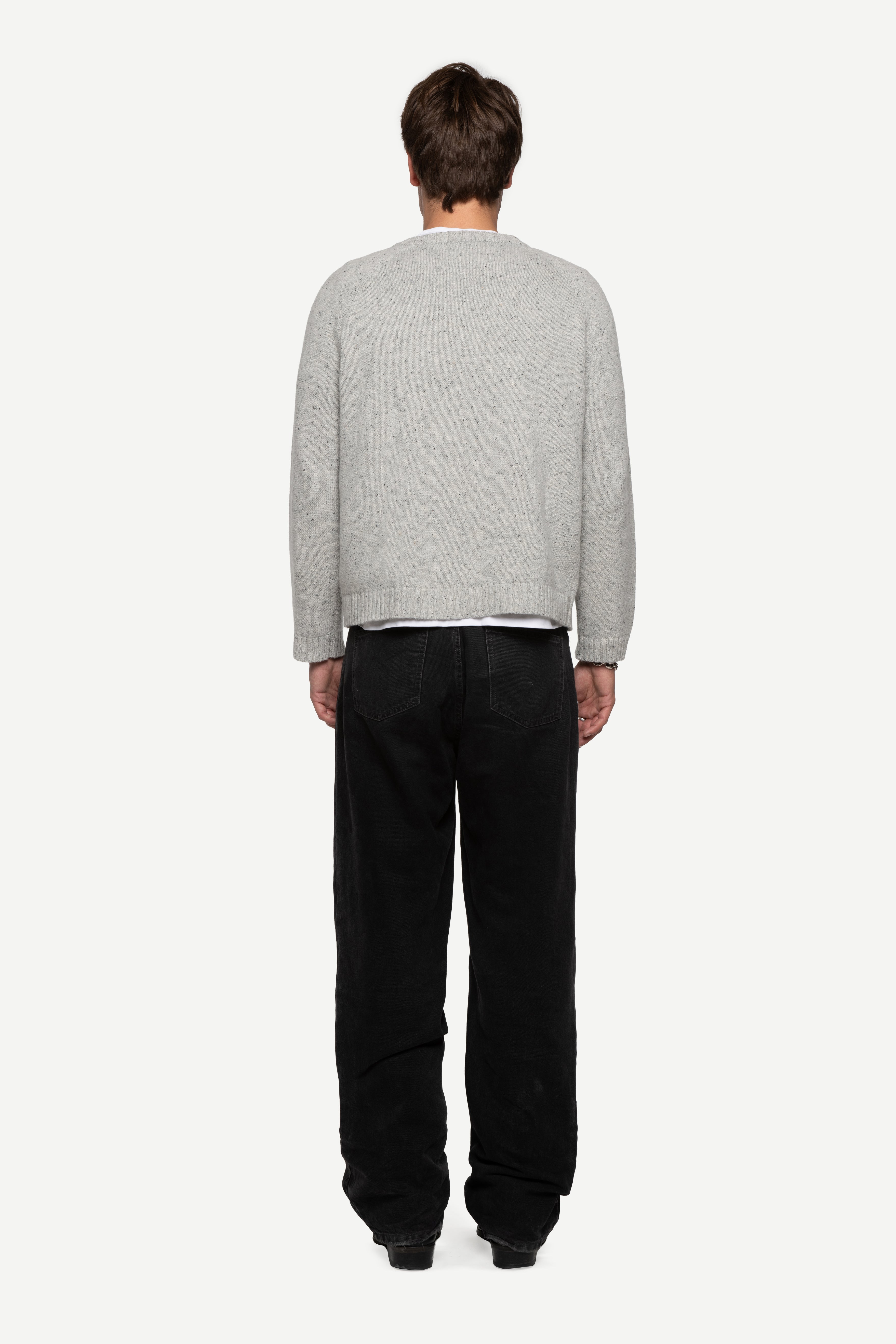 back view of man wearing a grey sweater made from a soft blend of wool and silk with black jeans on a white background