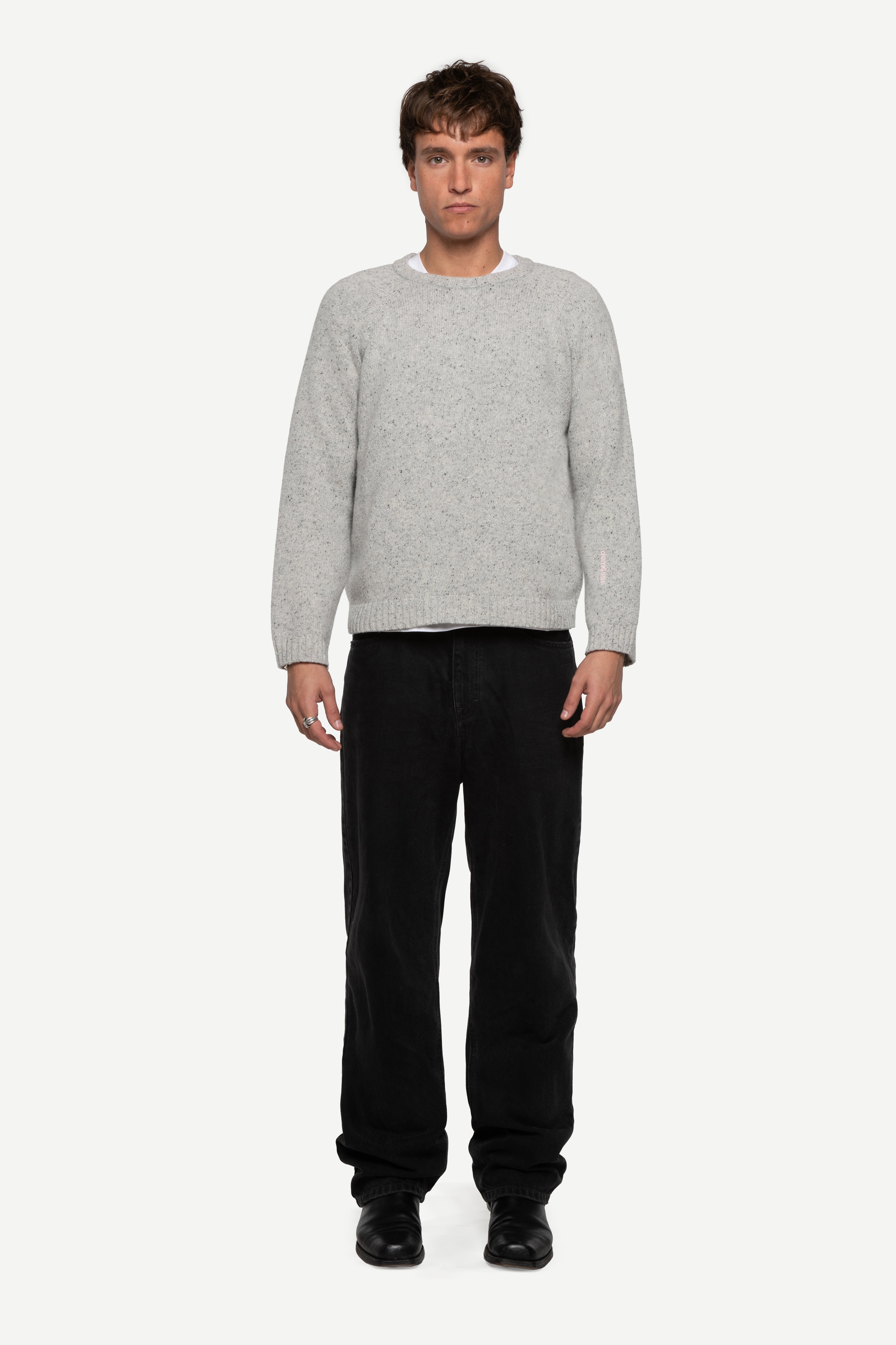 front view of man wearing a grey sweater made from a soft blend of wool and silk with black jeans on a white background