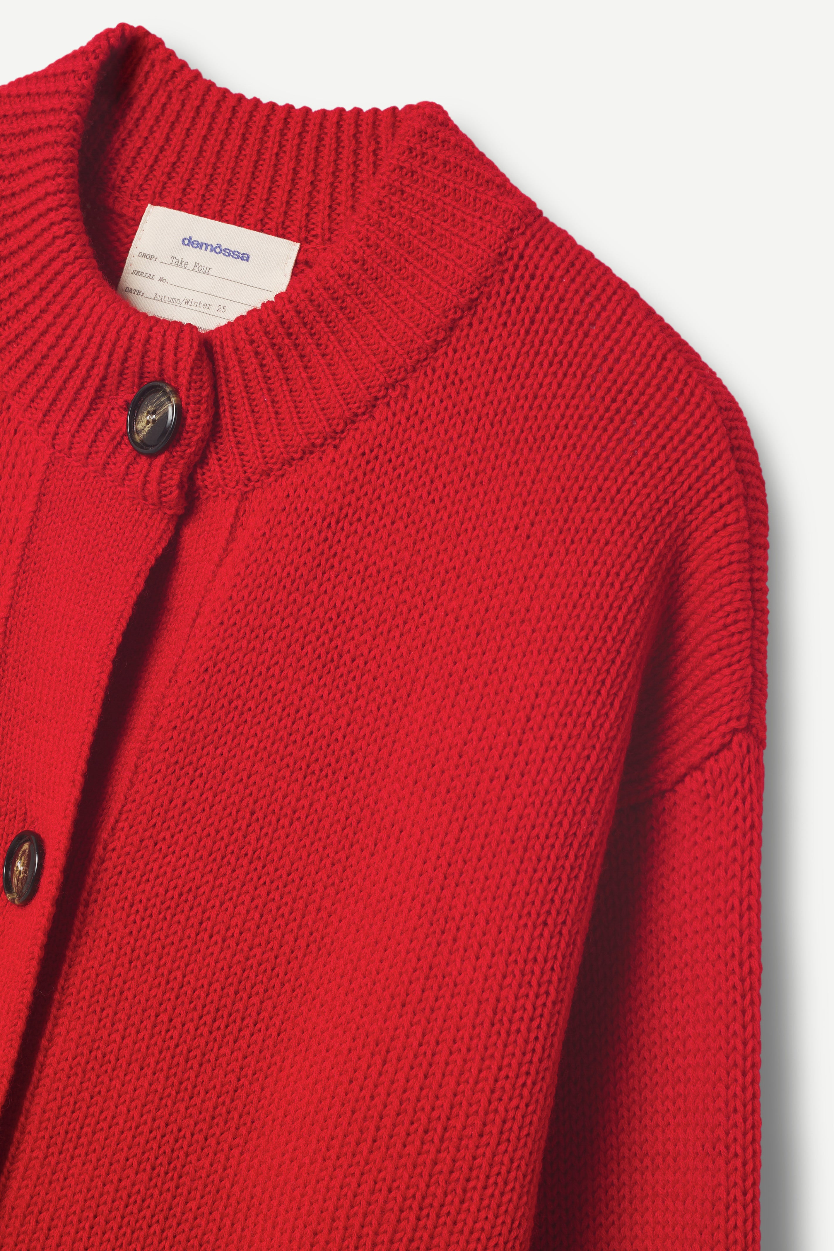 Red knitted cardigan with button details on a light gray background