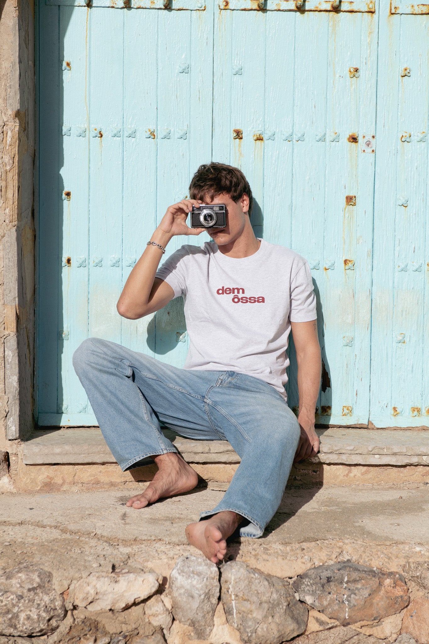 Person taking a photo with a camera in front of a rustic blue door.