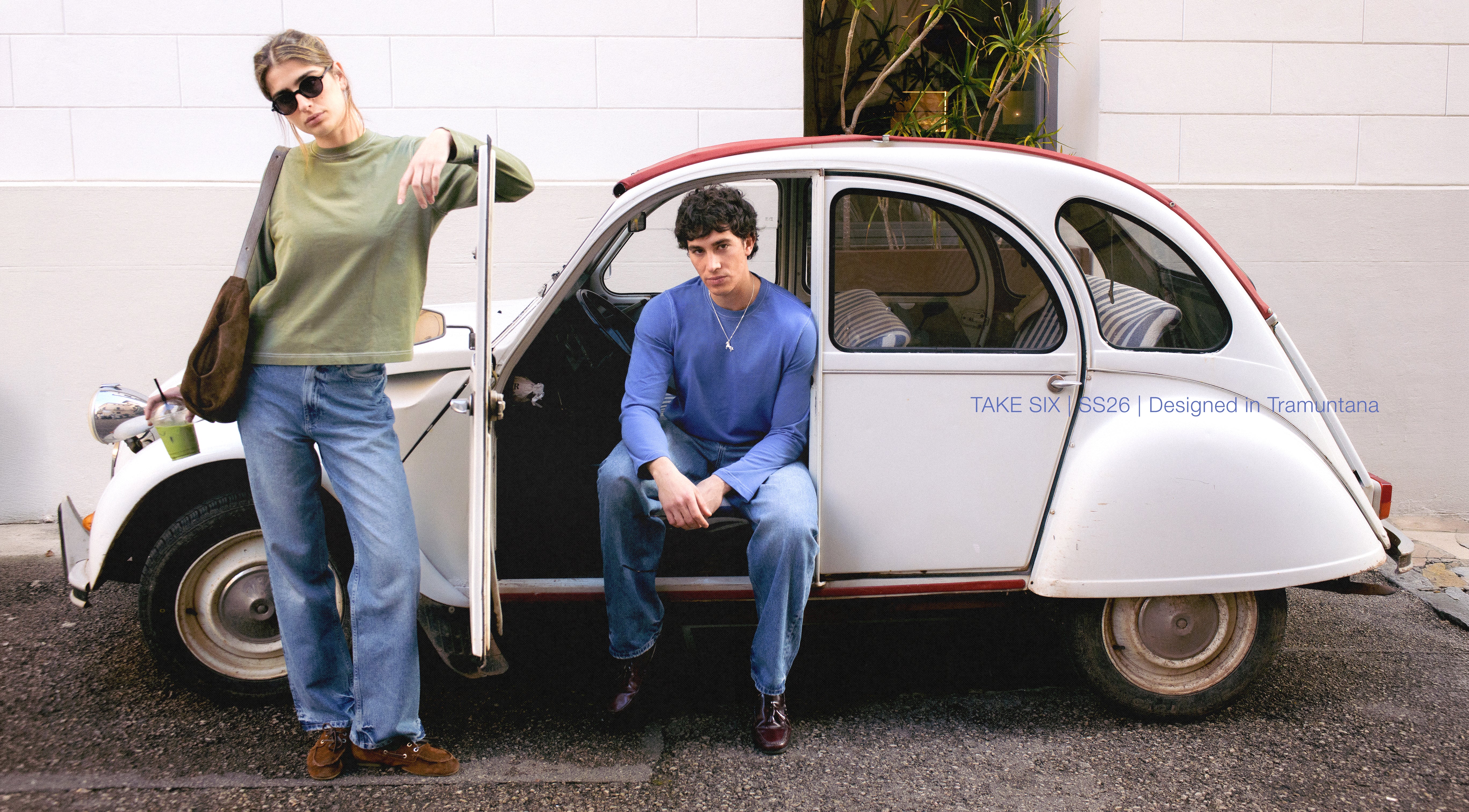 Two people with a small vintage car on a street.