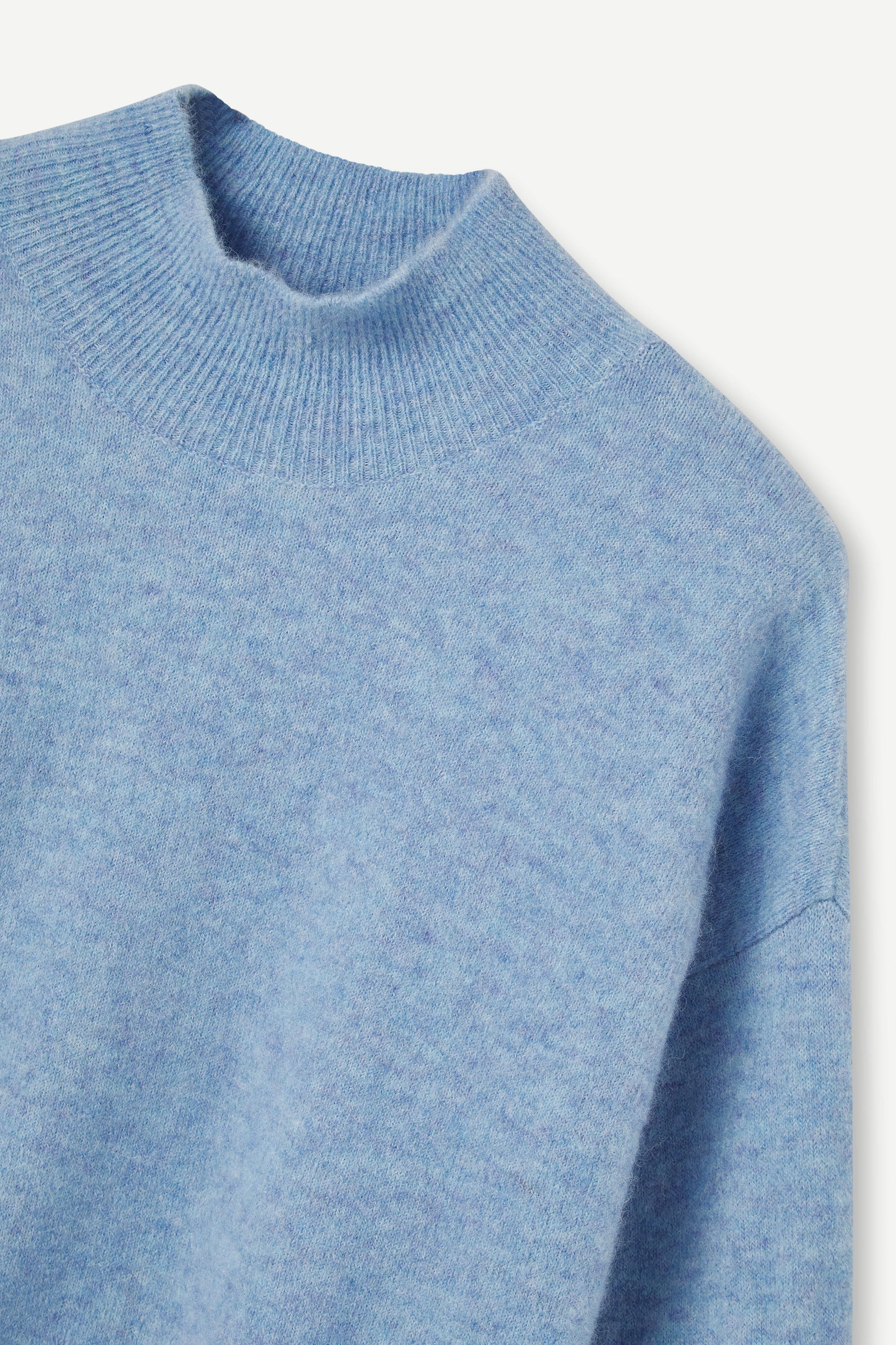 Close-up of a blue knitted sweater on a light gray background