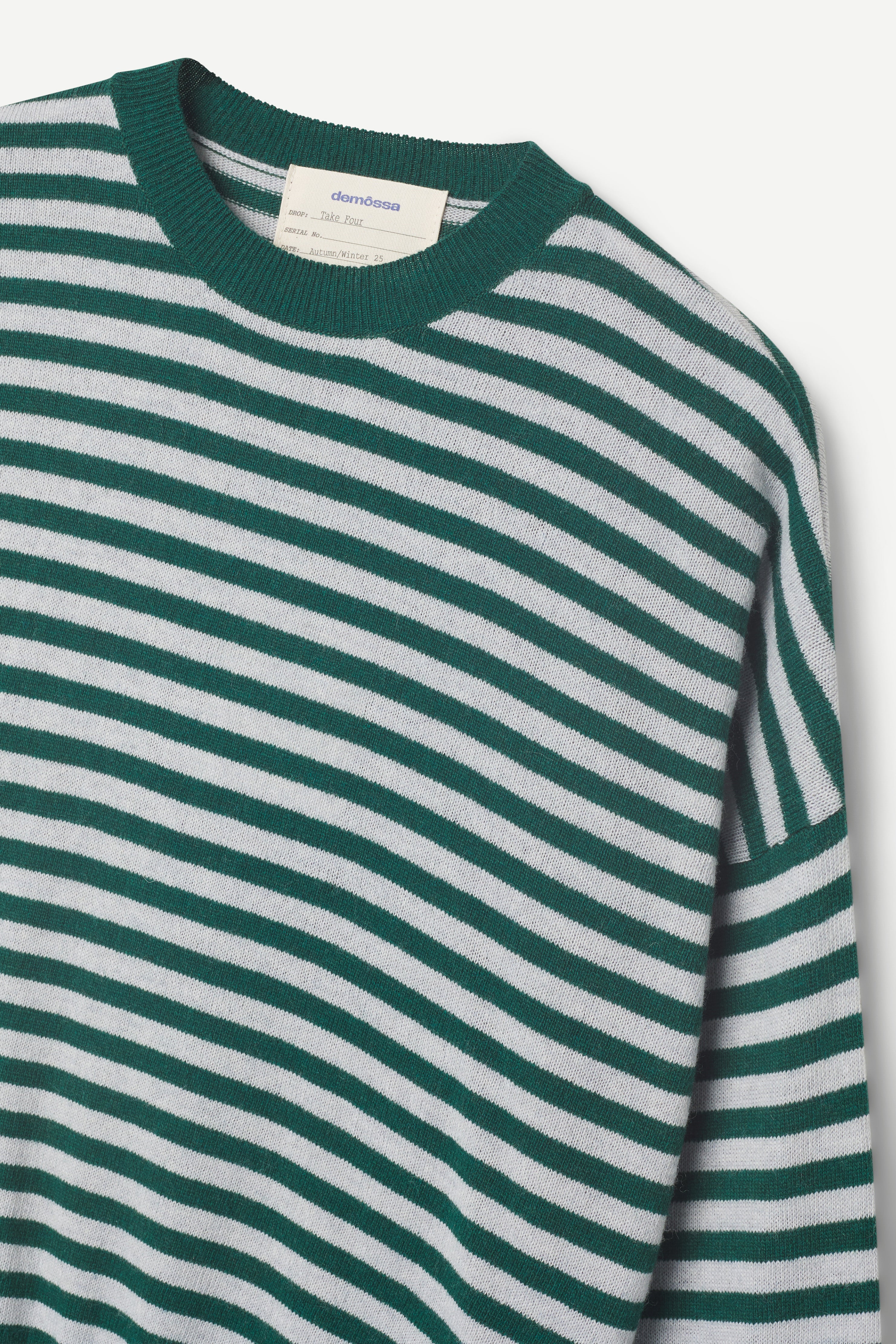 Green and white striped sweater with a brand label on a light gray background