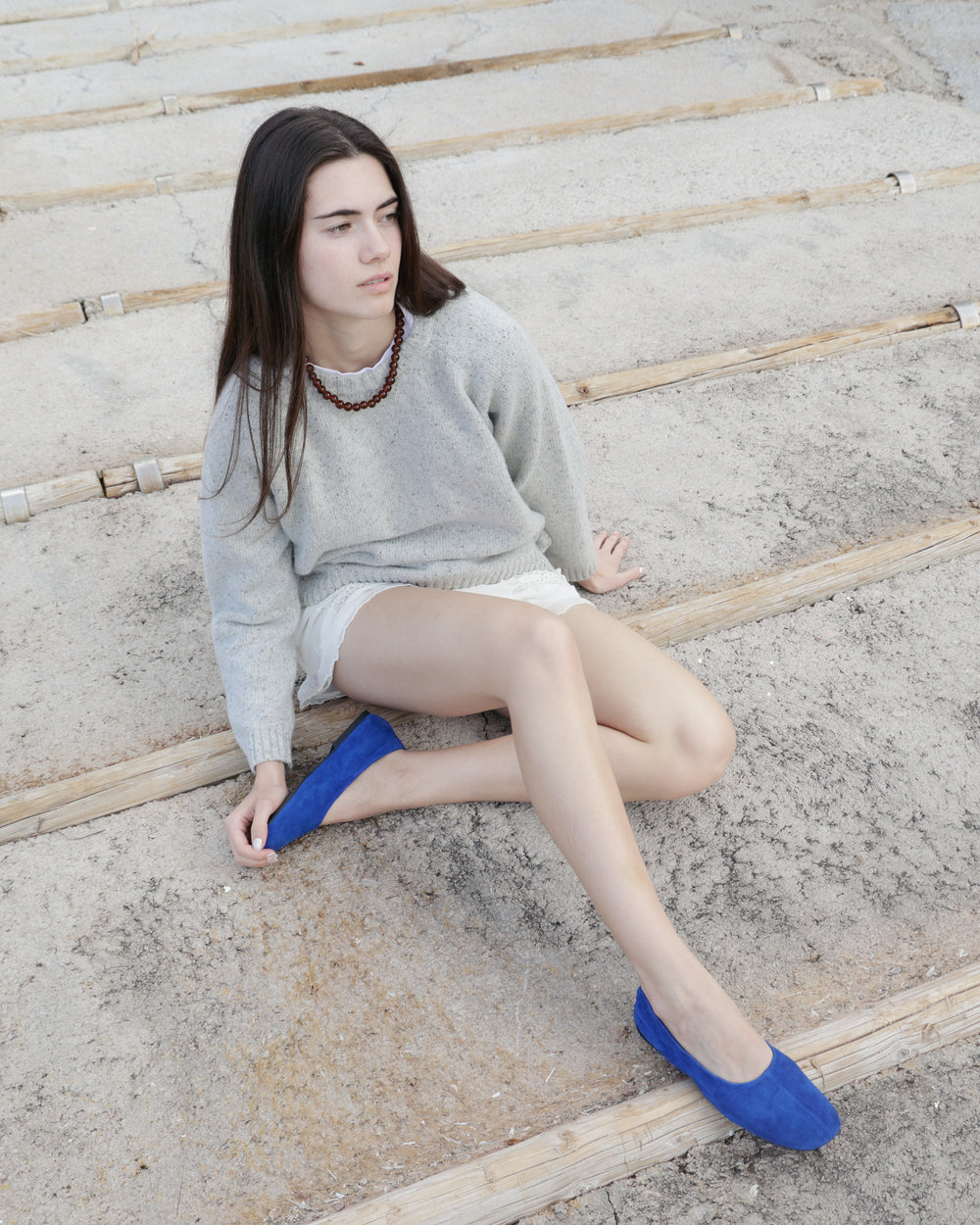 Woman sitting on a concrete surface wearing blue shoes