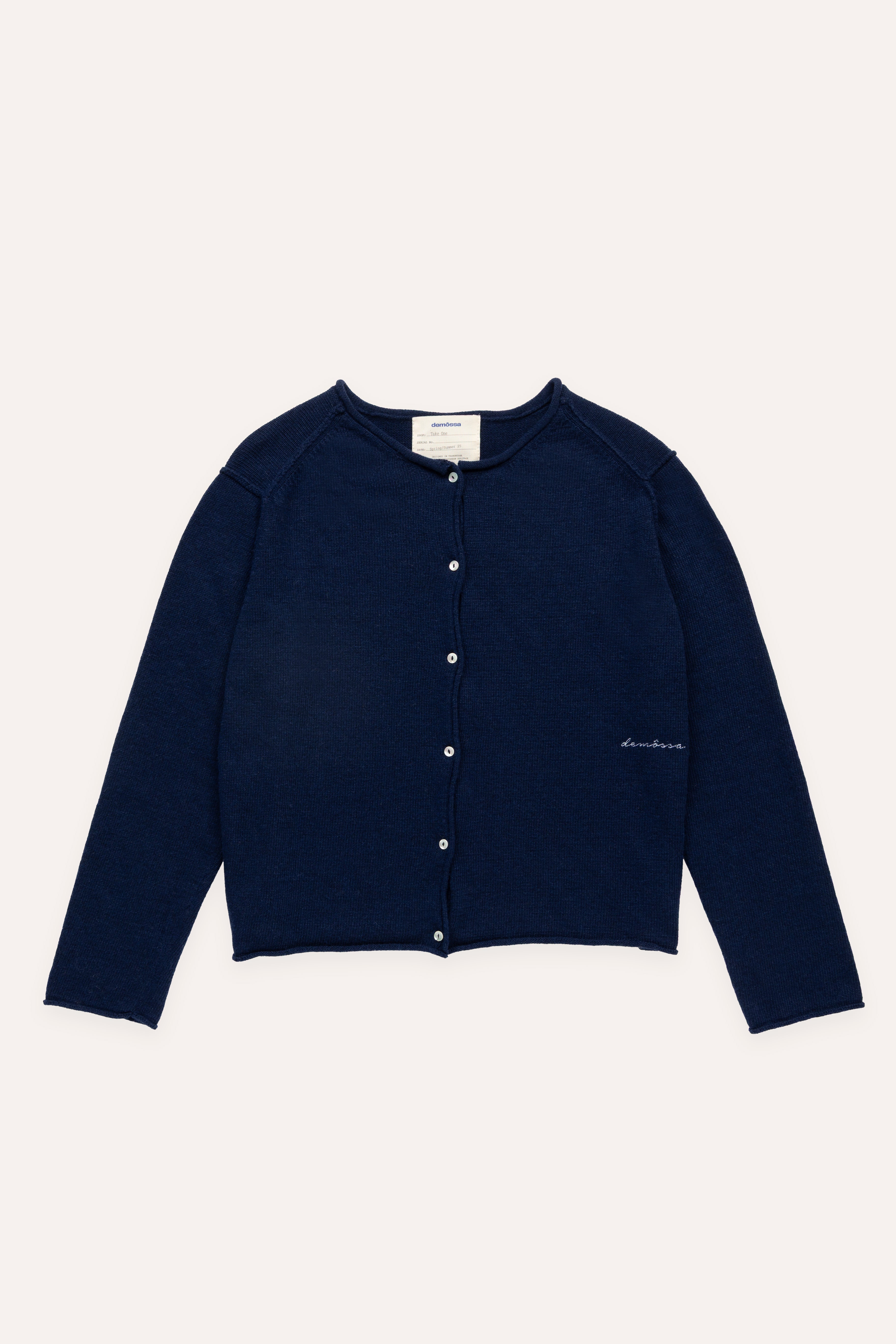 Flat lay of navy buttoned cardigan with raw-edge finish and Demossa logo embroidered on right front side