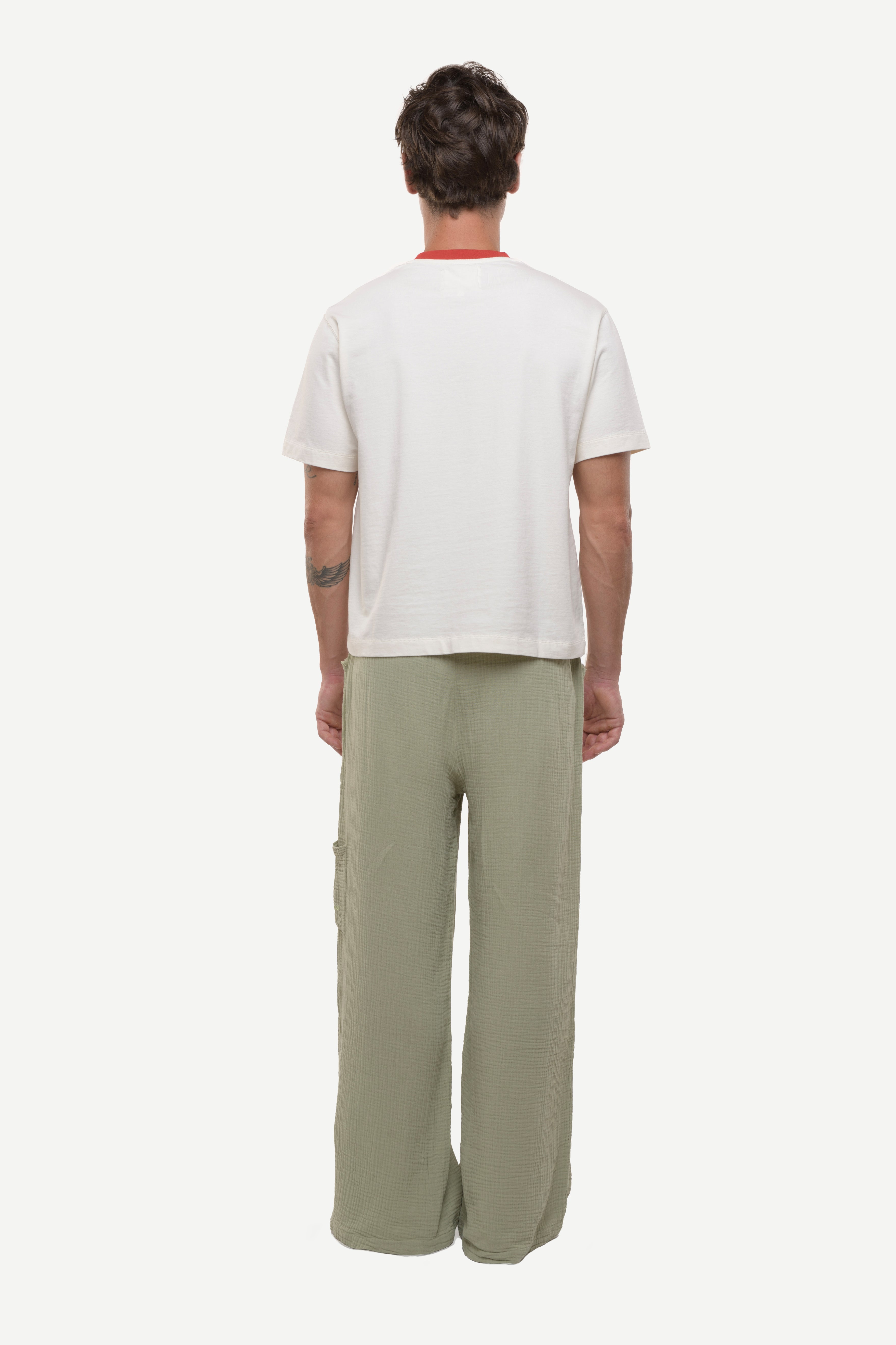Back view of man wearing a white t-shirt with red collar rib and green cotton pants white background