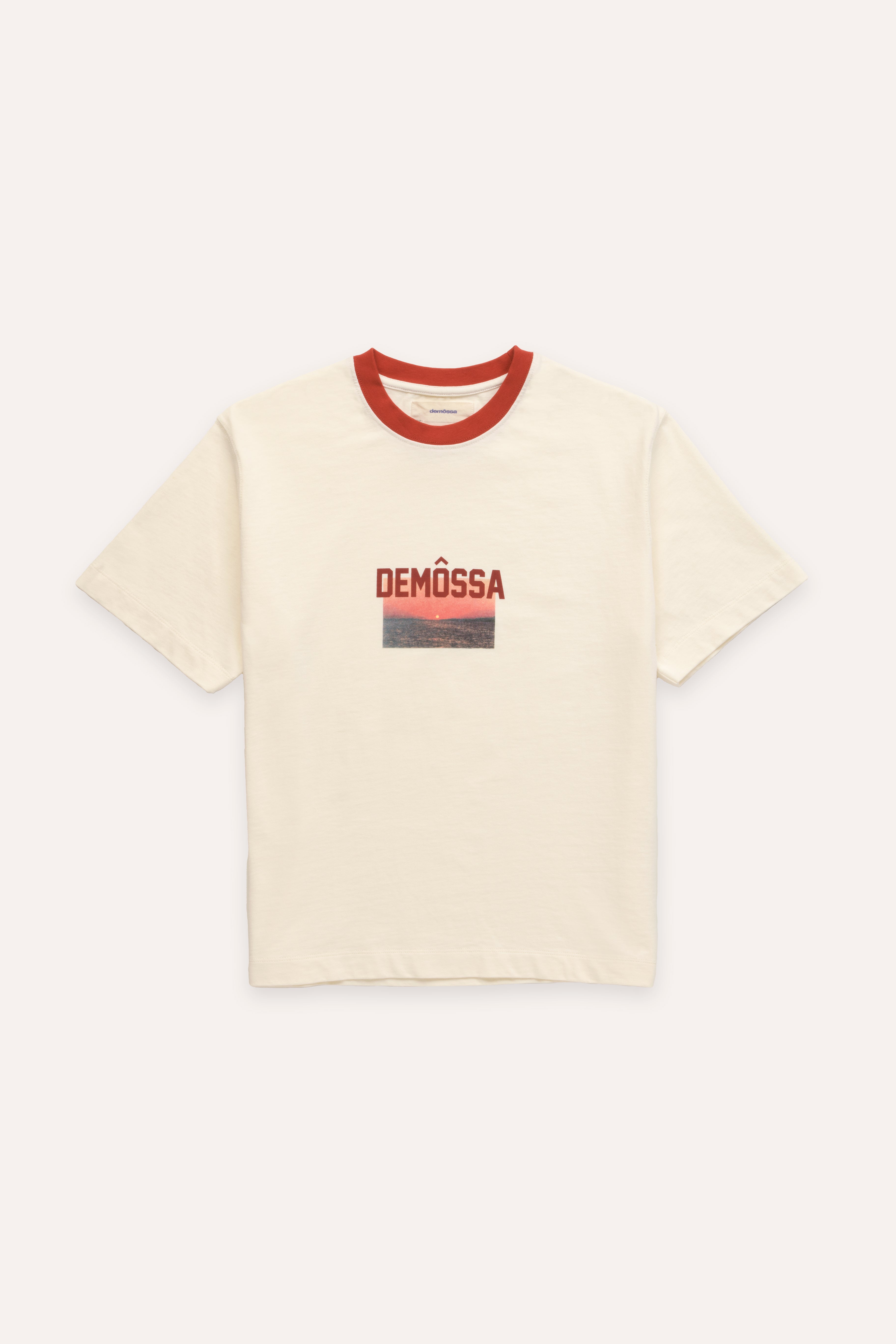 Beige t-shirt with red neckline and 'DEMOSSA' logo and a sunset graphic on a white background