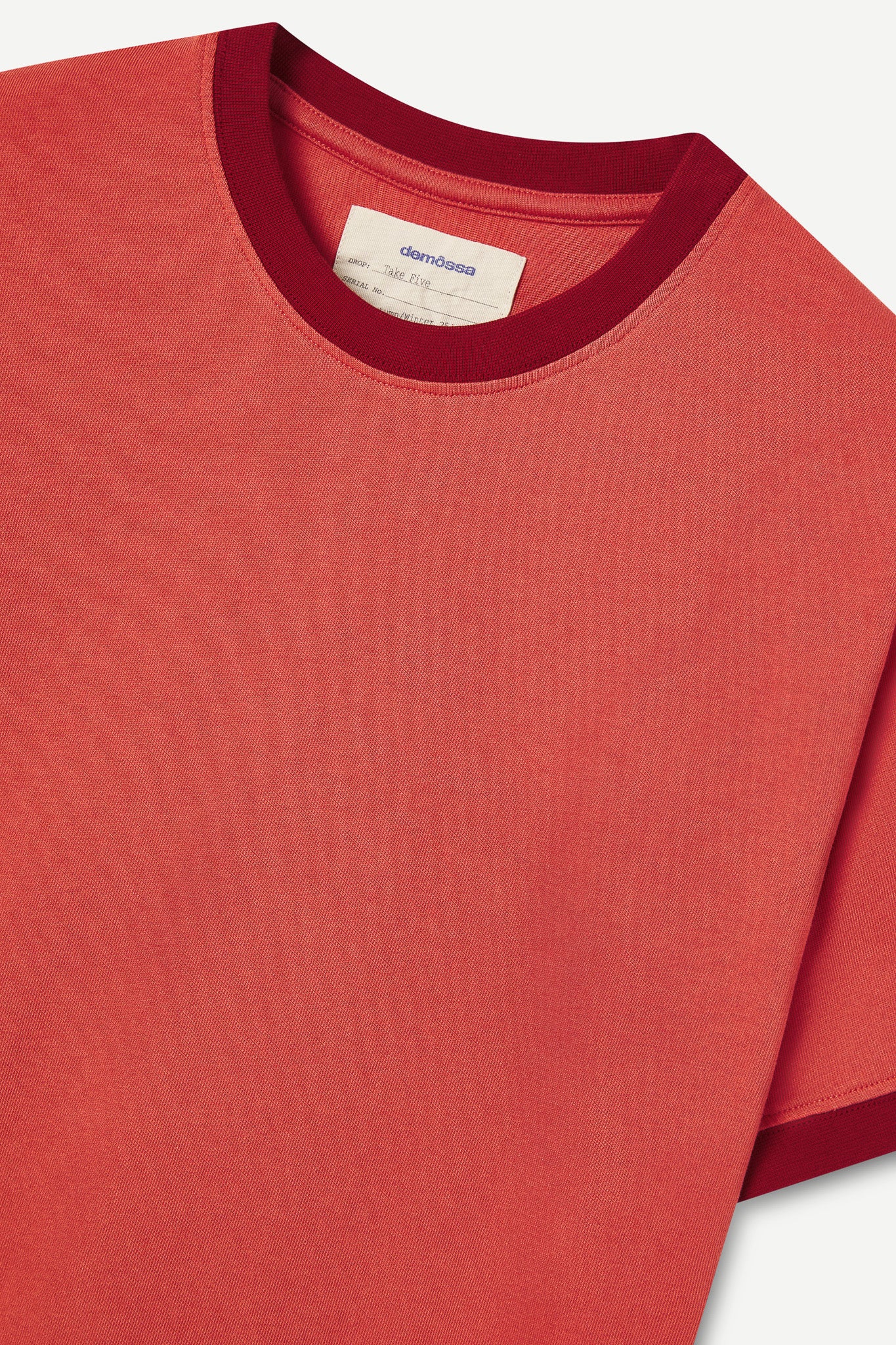 Red t-shirt with a visible brand label on a white background