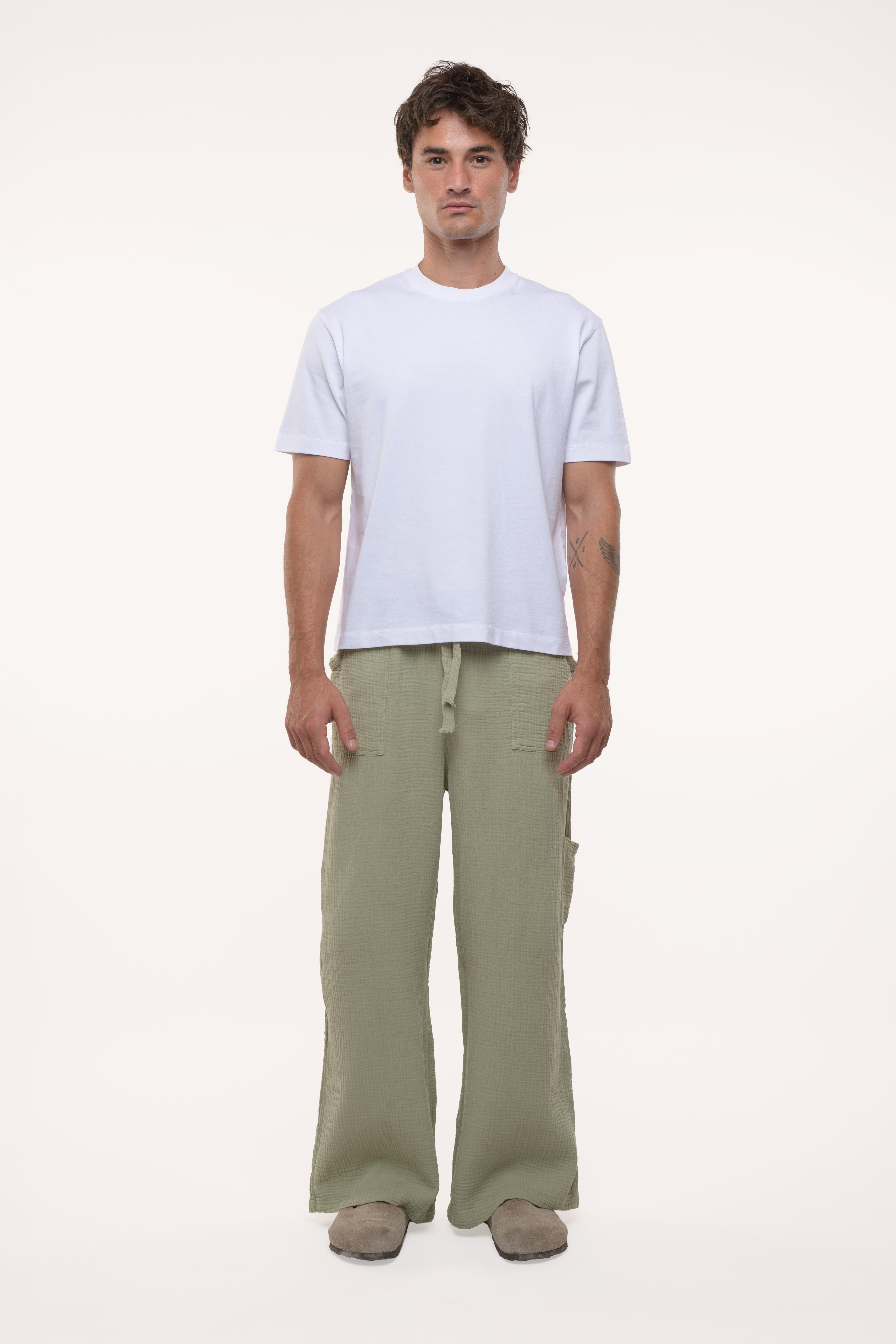 Man wearing a white t-shirt and green cotton pants on a white background
