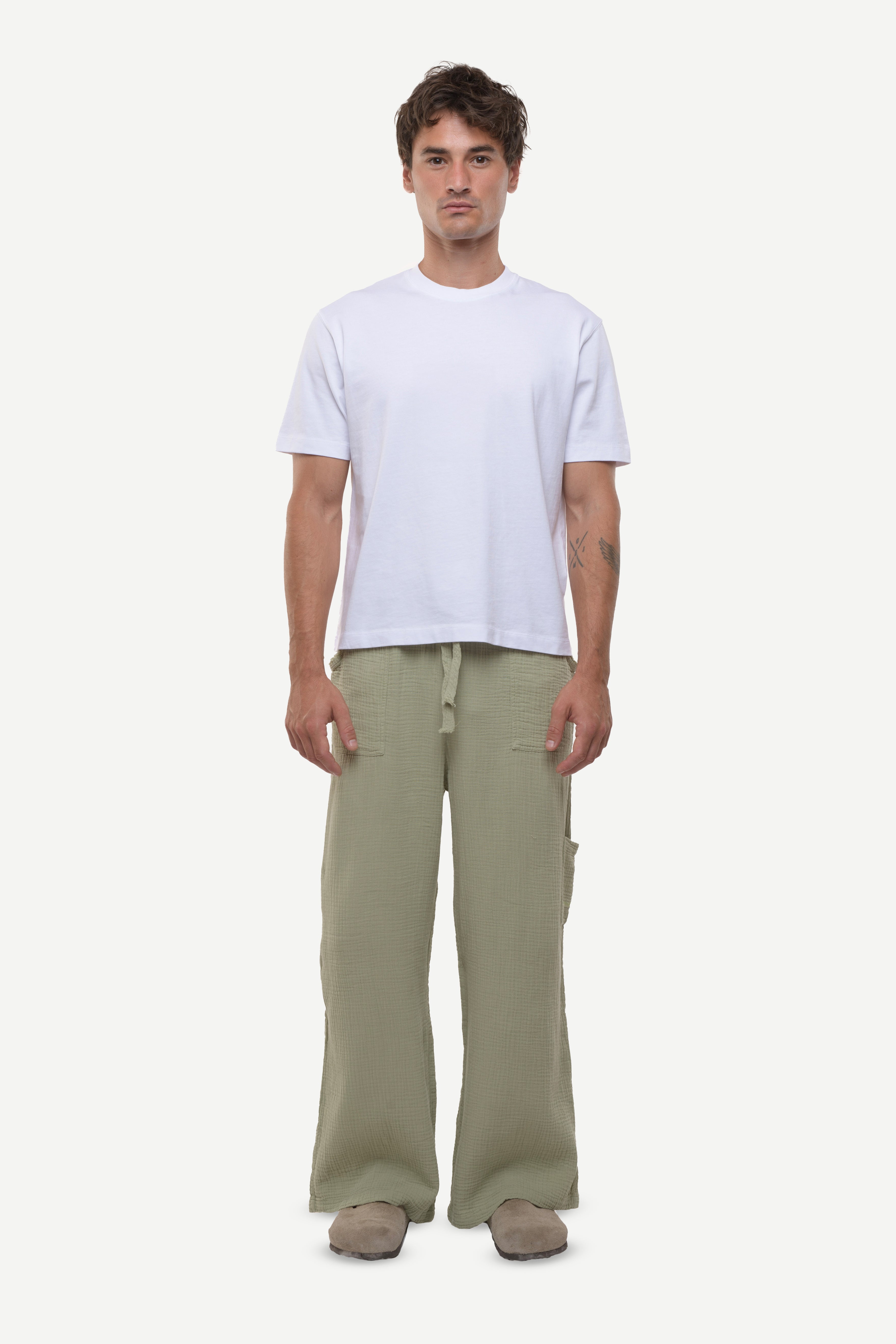 Man wearing a white t-shirt and cotton green pants on a white background