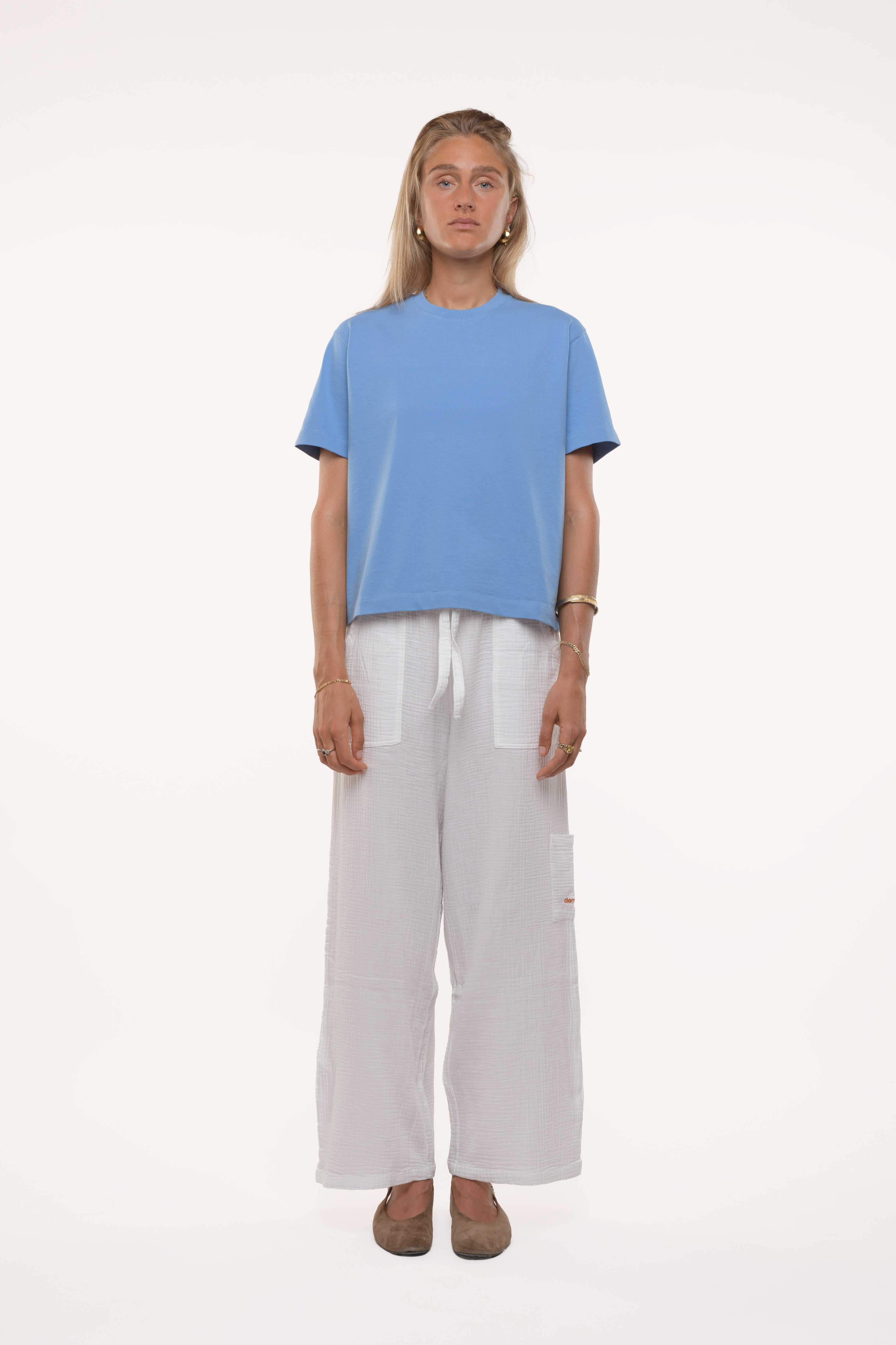 Woman wearing a blue t-shirt and white pants on a white background