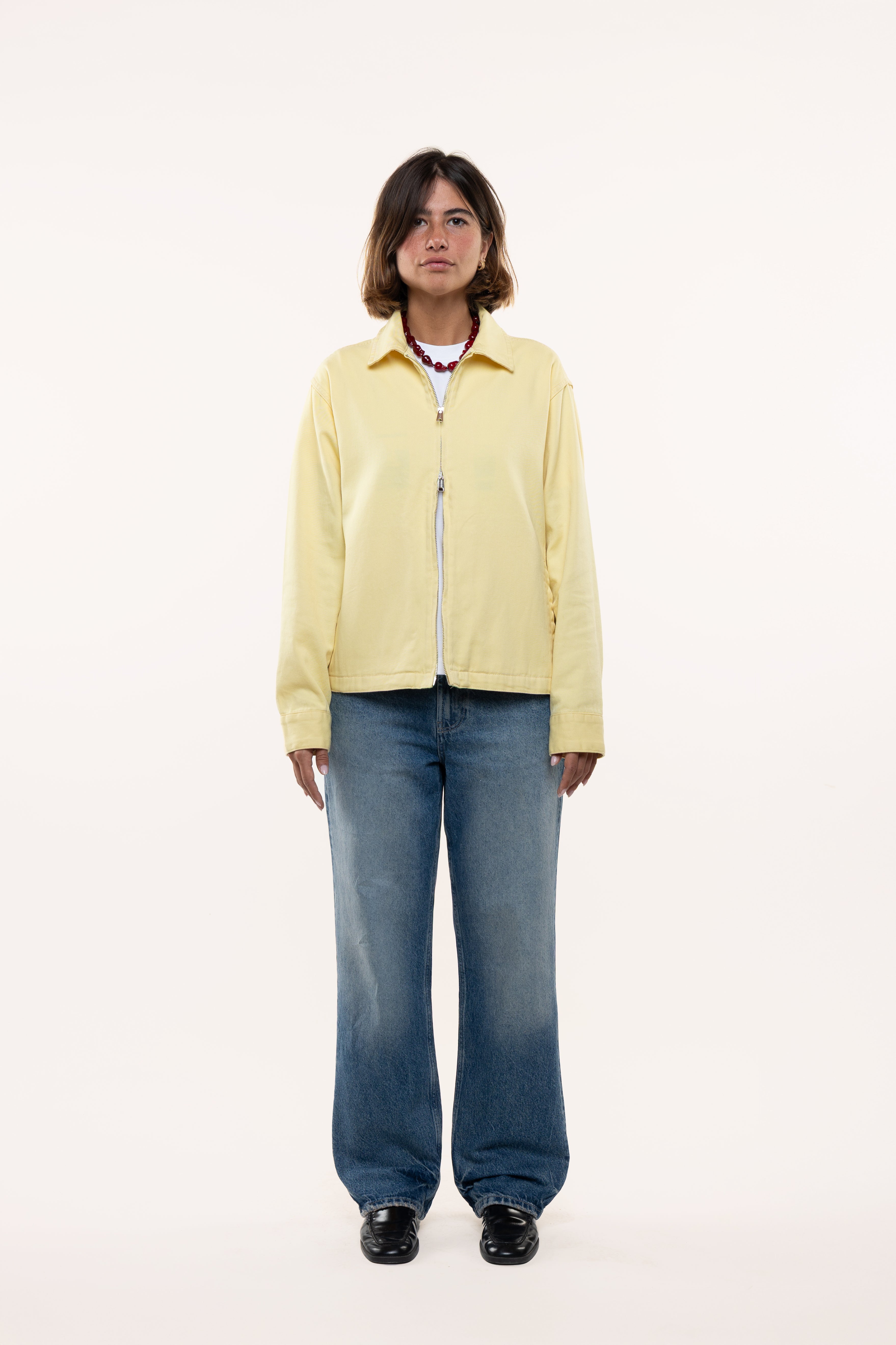 Girl wearing a light yellow jacket and blue jeans on a white background
