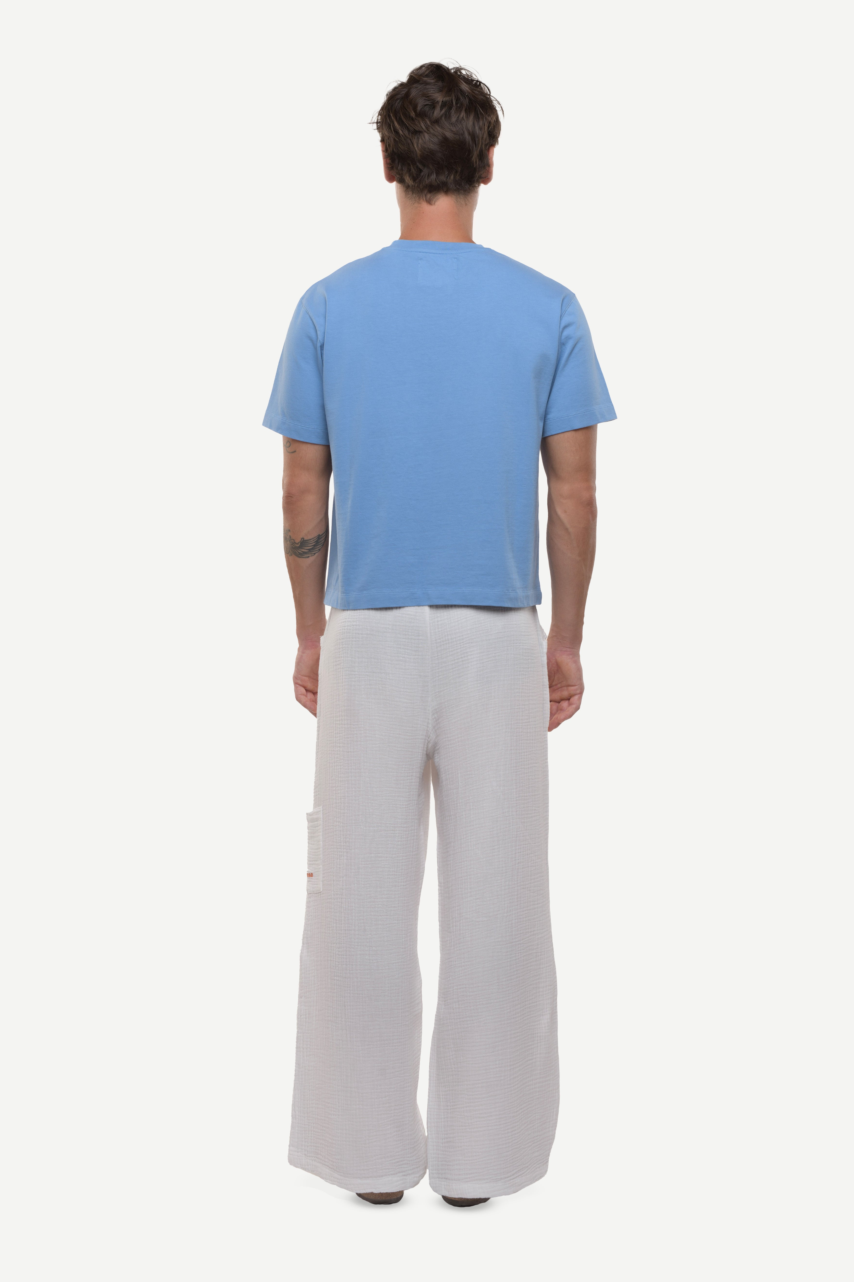 Back view of man wearing a blue t-shirt on a white background