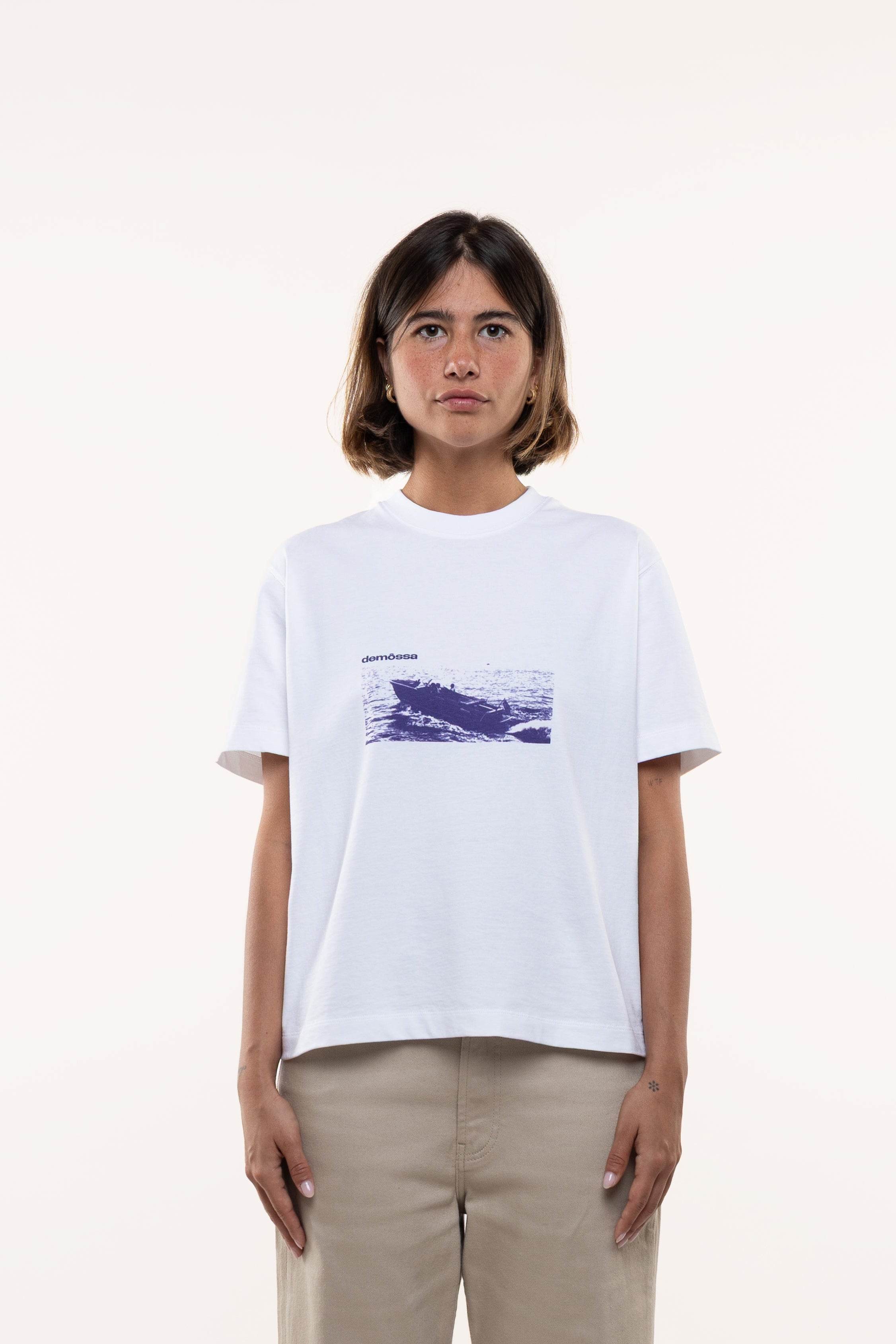 Woman wearing a white t-shirt with a graphic design on a plain background