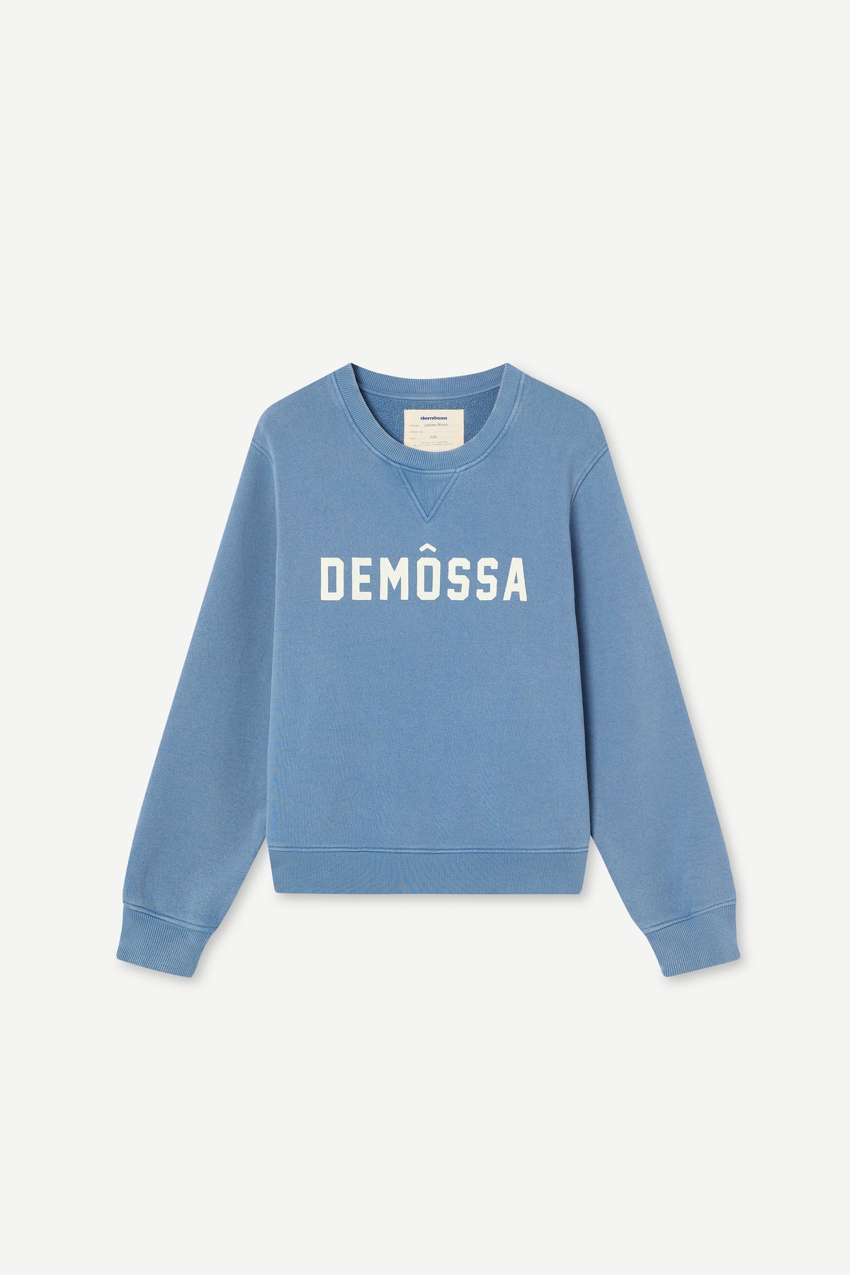 A light blue crewneck sweatshirt with 'DEMÓSSA' printed in white across the chest, displayed on a clean off-white background.
