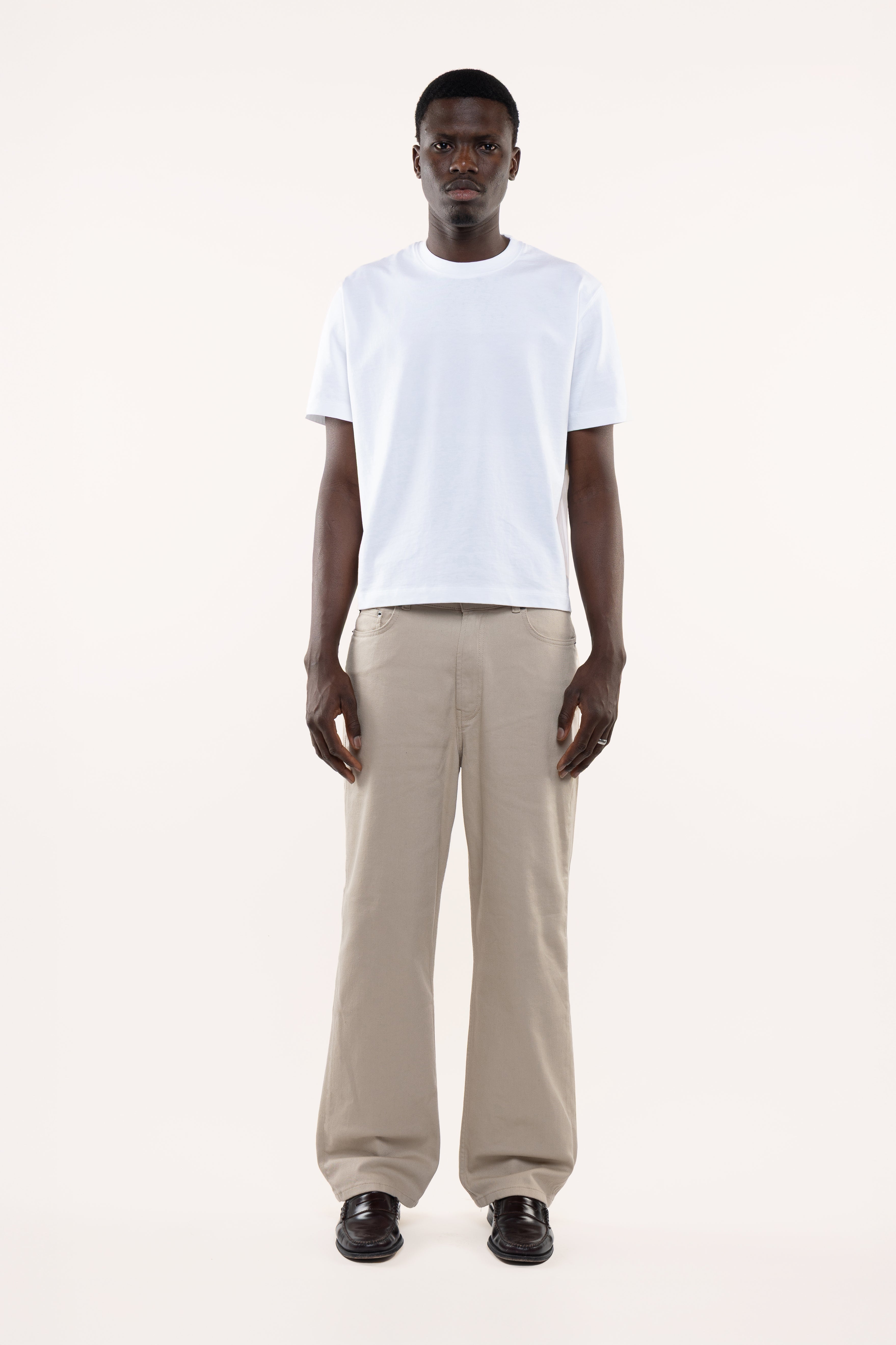Man wearing a white t-shirt and beige pants on a white background