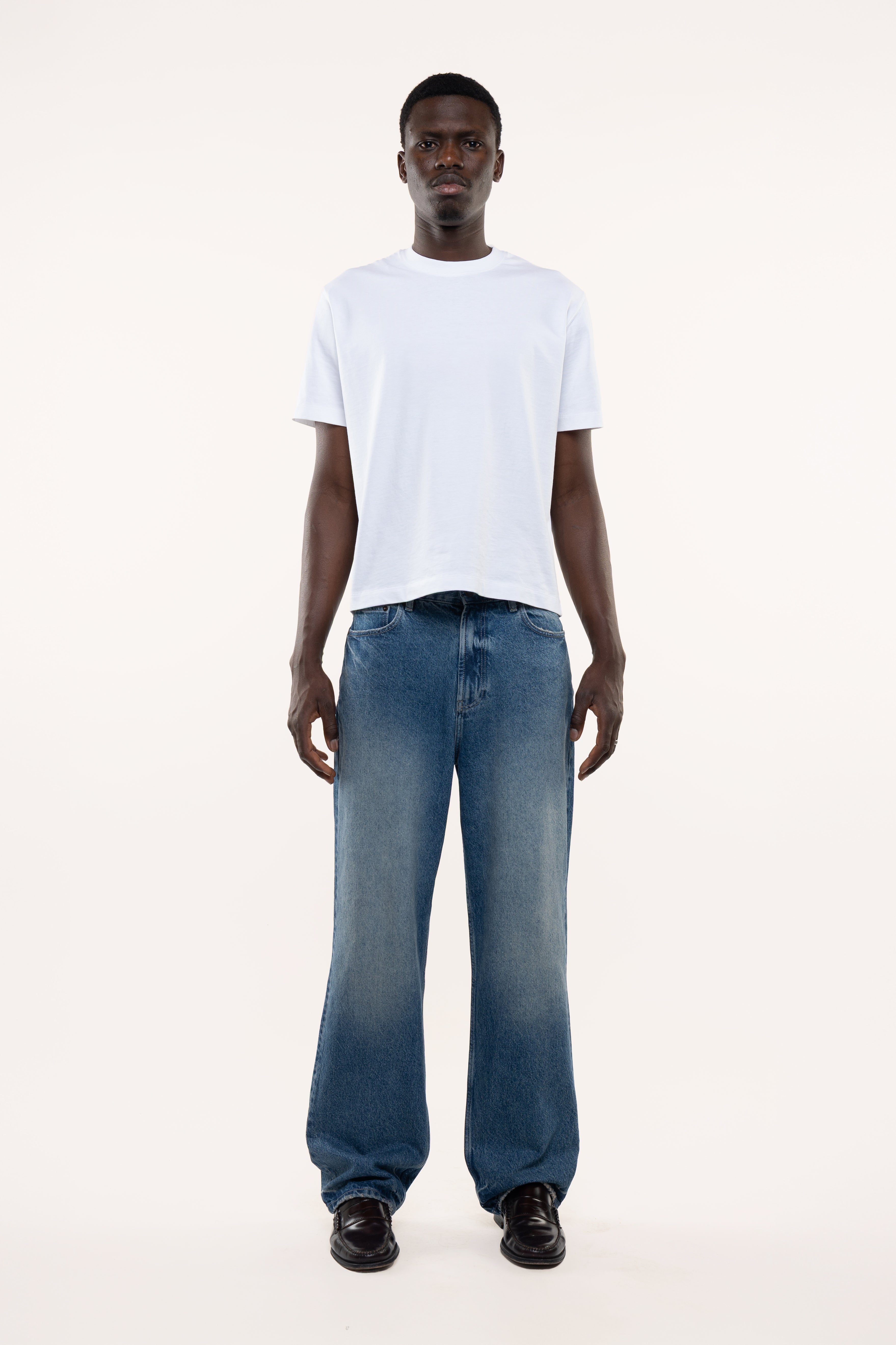 Man wearing a white t-shirt and blue jeans on a white background