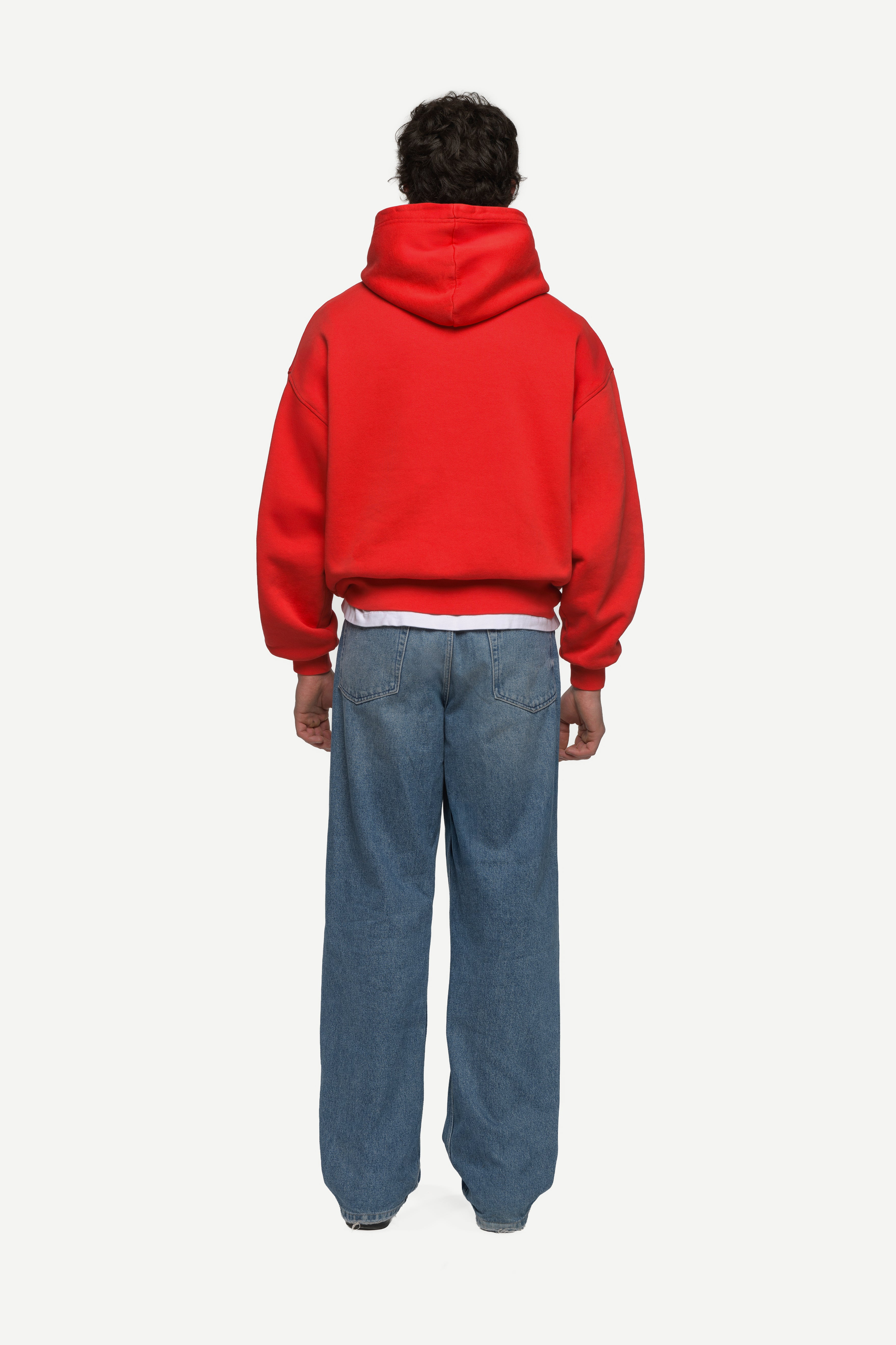 back view of man wearing a red hoodie and blue jeans on a white background